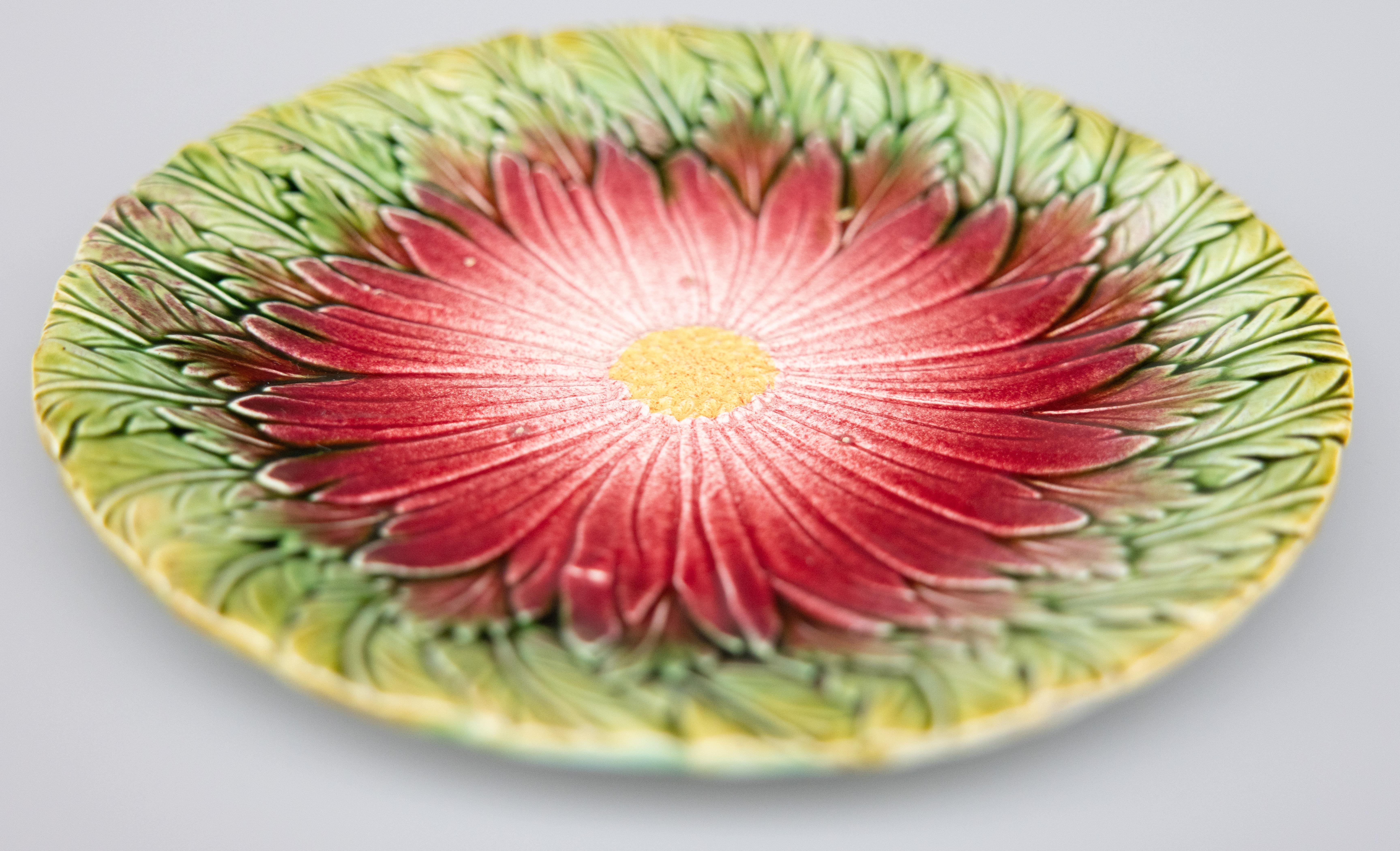 A lovely antique 19th-Century French majolica daisy flower plate, attributed to Orchies, circa 1890. Unmarked. This gorgeous plate has a hand painted dark pink / rhubarb / cranberry daisy on a green leaf background. It would be lovely added to a