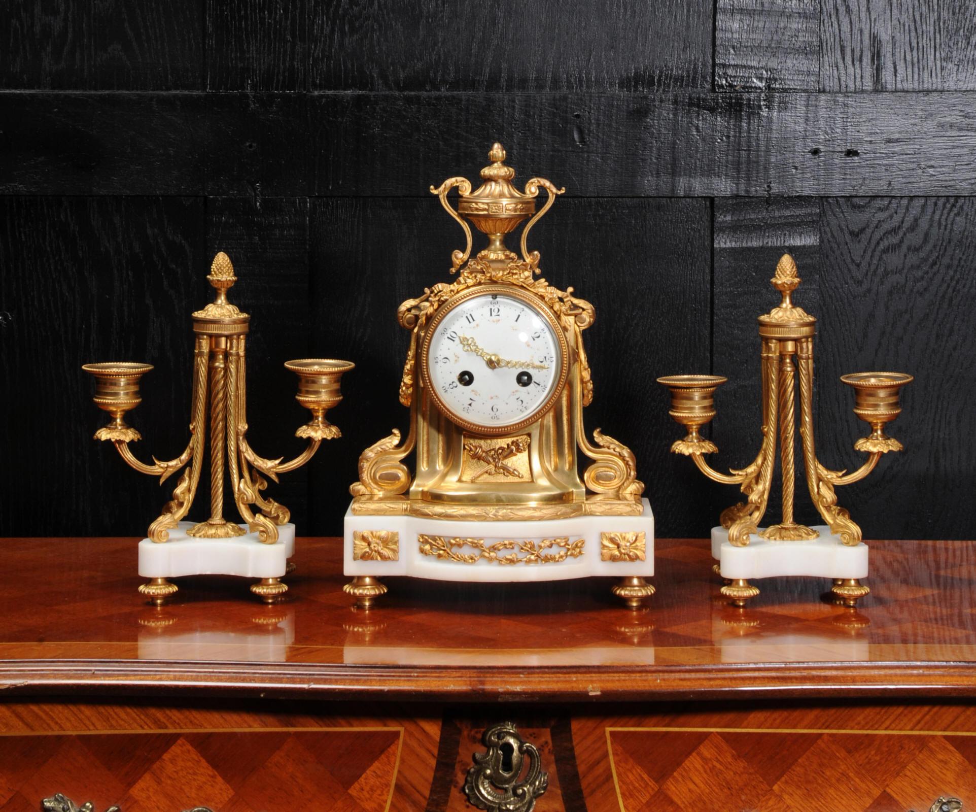 A fine and elegant original antique French Louis XVI style clock set, circa 1860. It is beautifully made of beautiful white marble mounted with very good quality ormolu (finely gilded bronze). To the sides are scroll brackets with acanthus leaves.