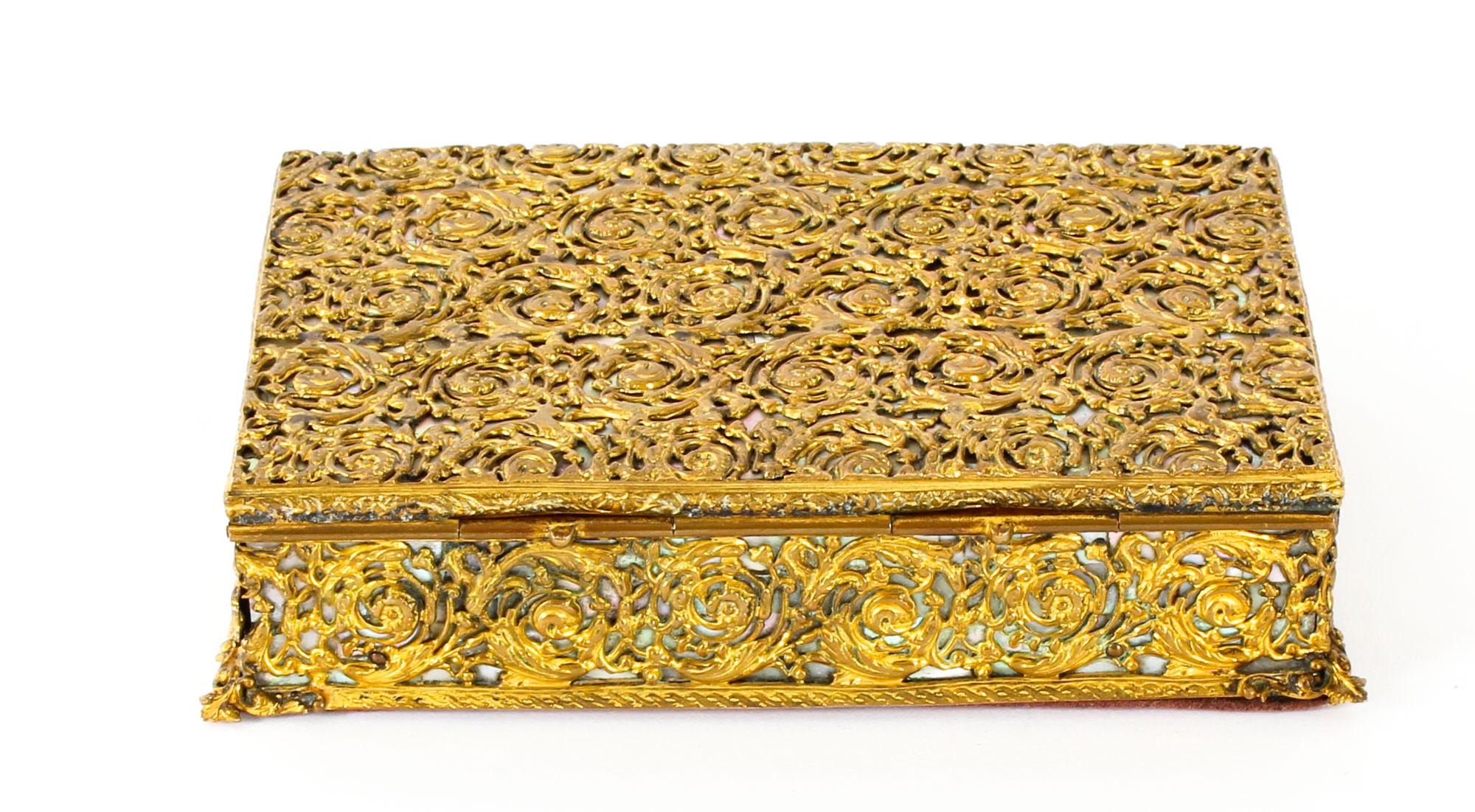 This is a beautiful antique gilded ormolu and mother of pearl casket, circa 1870 in date.
 
The top, front, sides and back feature beautifully cast ormolu decorative trellis work over of a mother of pearl ground.
 
The interior is lined with the