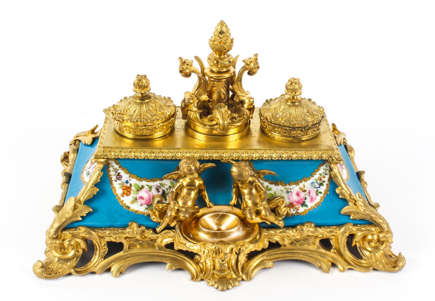 This is a wonderful antique French ormolu inkstand, mounted with Bleu Celeste Sèvres porcelain panels that have been beautifully gilded and painted with floral garlands, circa 1870 in date.

The inkstand with a central ink reservoir and inkwell