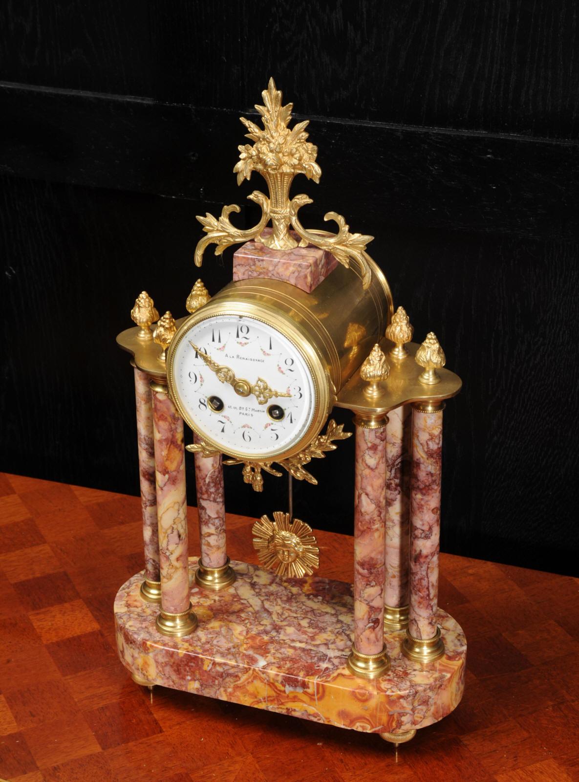 A stunning antique French portico clock, circa 1900. It is made of the most beautiful variegated specimen marble, with variegated reds and oranges, mounted with finely finished ormolu (gilded bronze). It is classical in style, the clock is mounted
