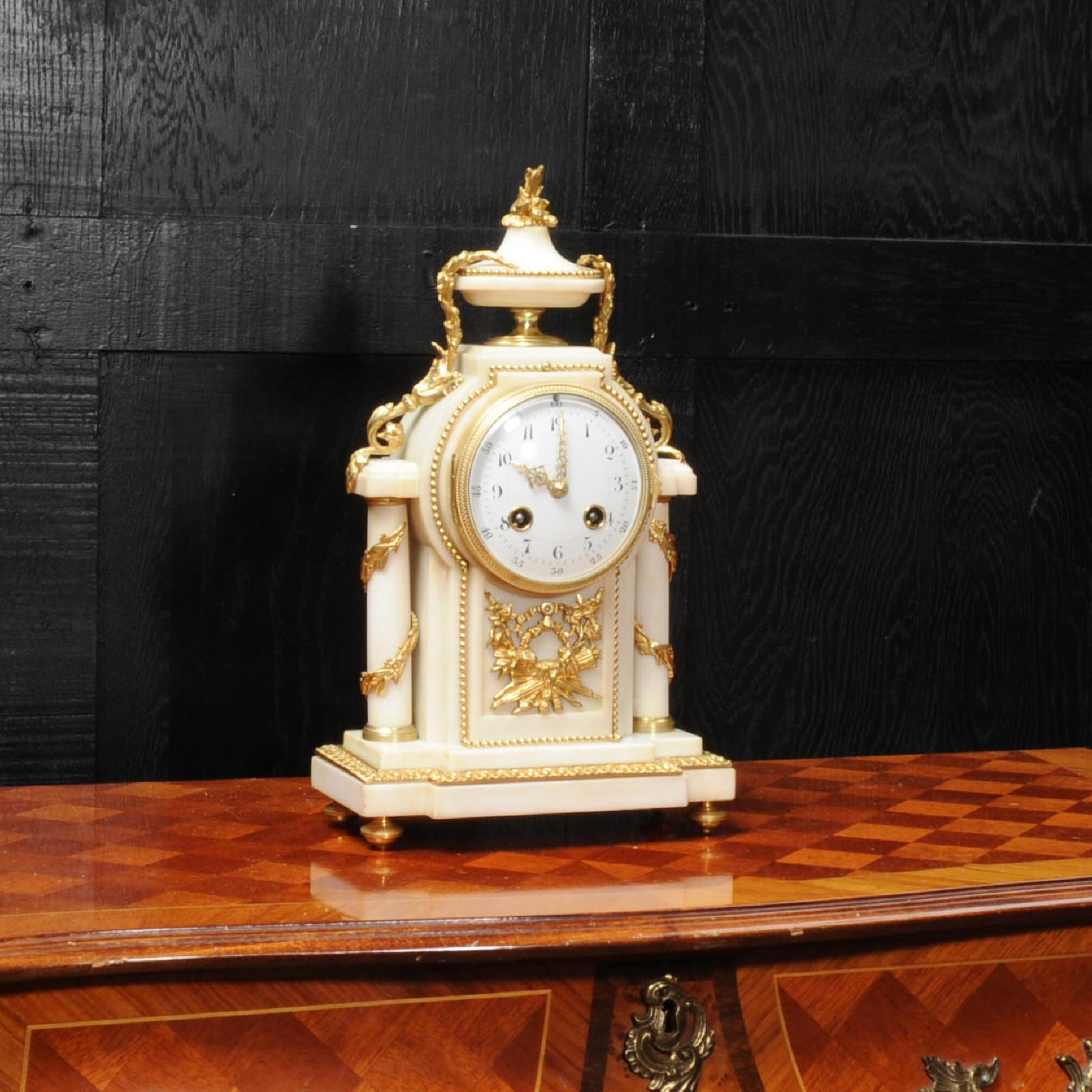 A beautiful antique French ormolu-mounted white marble boudoir clock, circa 1900. It’s of elegant Louis XVI style, classical columns wrapped with foliage and an urn to the top with foliage draped down each side. To the front is a motif of a quiver