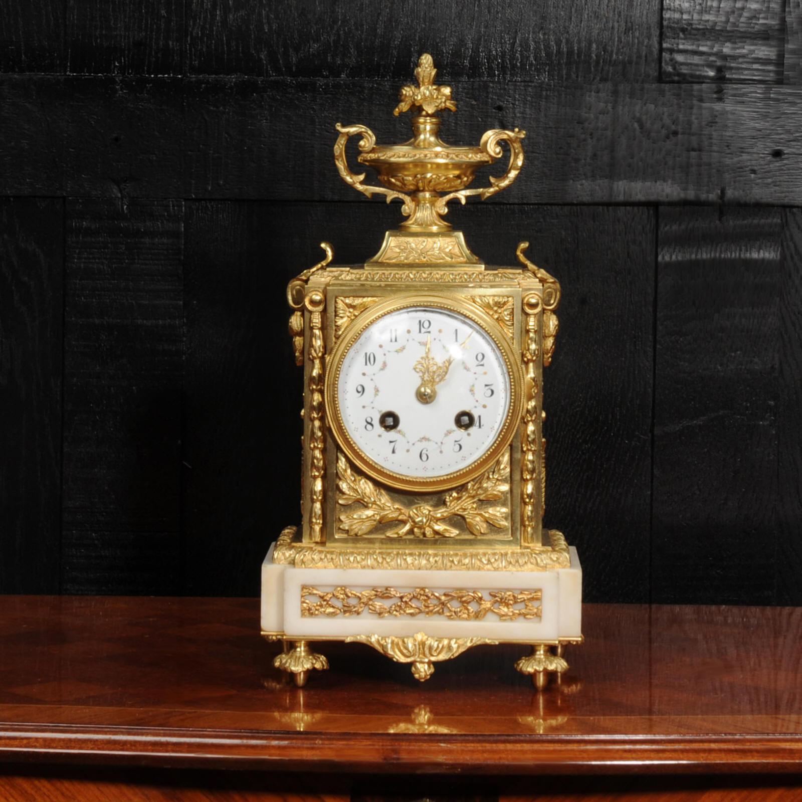 A beautiful classical clock made in the style of Louis XVI by Samuel Marti. Stunning ormolu (finely gilded bronze) mounted on a marble base. It is decorated with an inset laurel swag, trailing acanthus and a classical motif to the sides. To the top