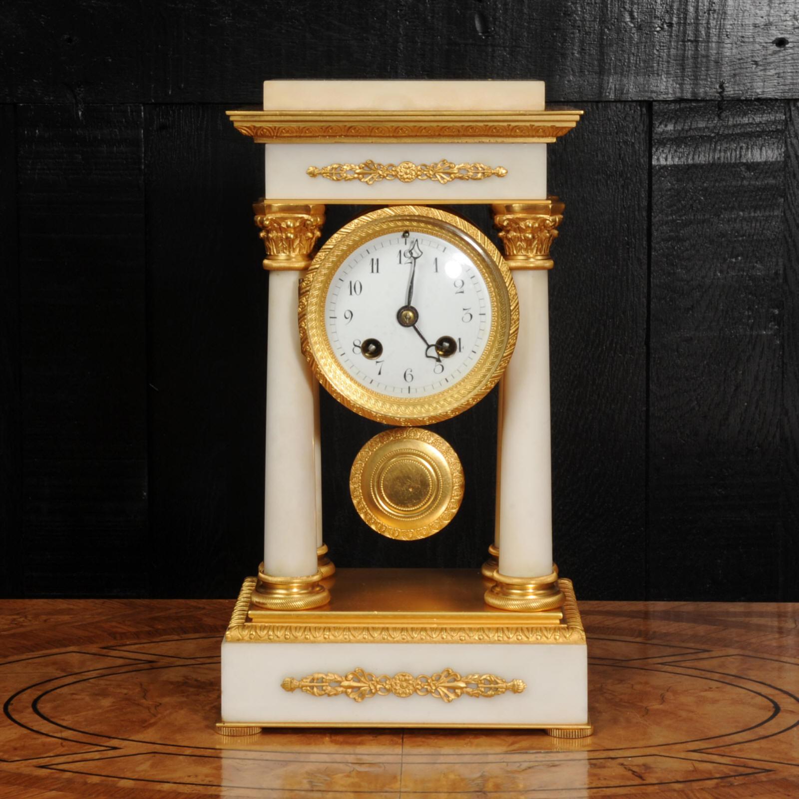 A beautiful small antique French portico clock retailed by the famous Maple & Co of London, circa 1890. Very well made in white marble and ormolu (finely gilded doré bronze). Neoclassical in design, four delicate Corinthian columns support the top