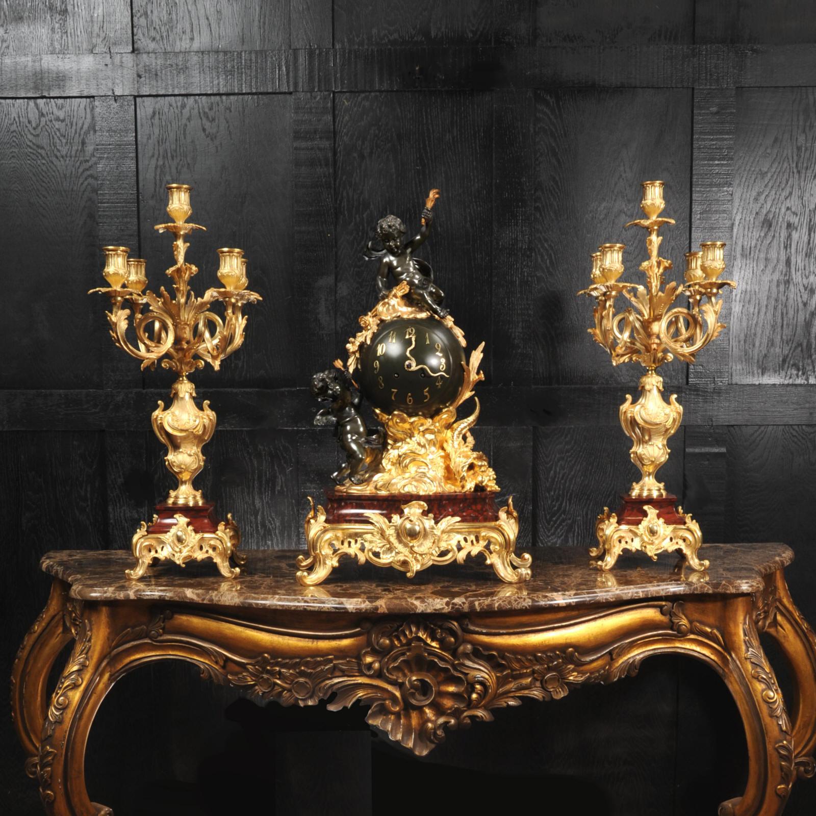 An exceptional antique French Louis XV style clock set, circa 1870. Beautifully made in ormolu (finely gilded Bronze Dore), patinated bronze and Rouge Griotte Marble. The clock is mounted in a bronze orb floating in the ormolu clouds. Cherubs