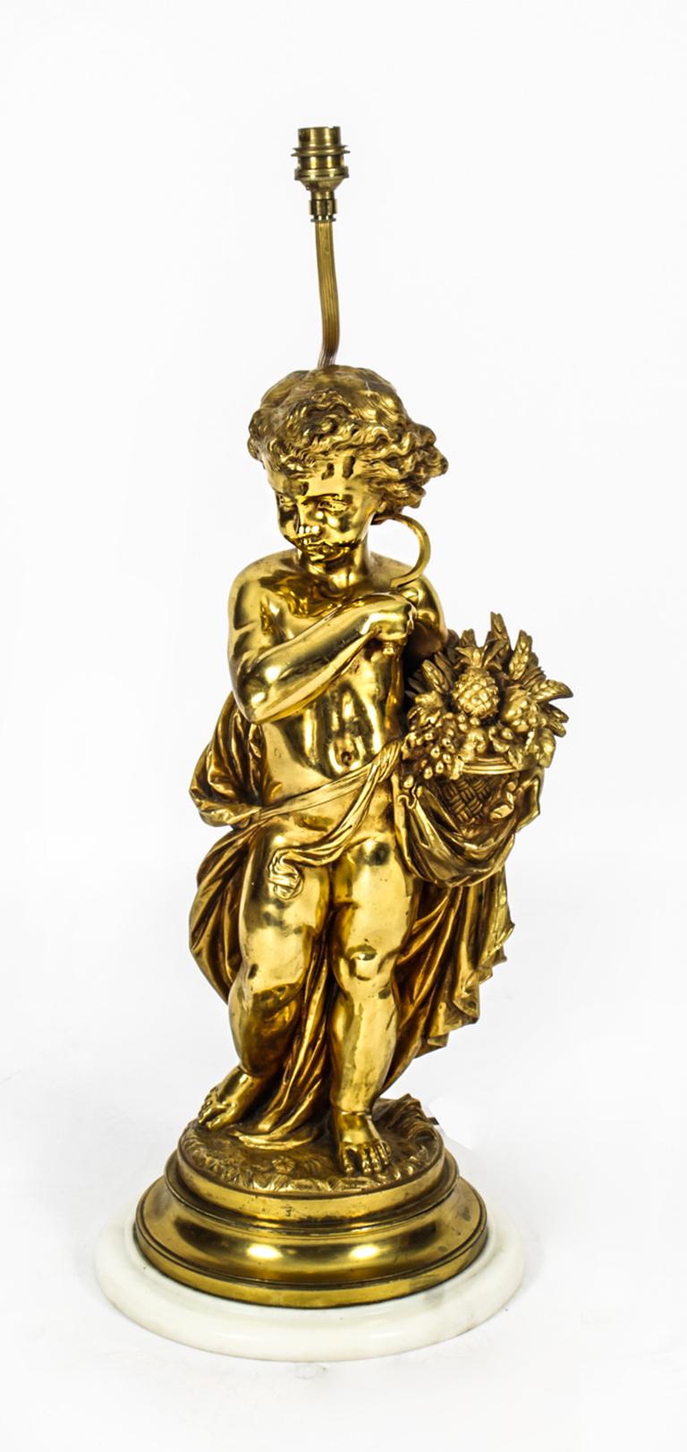 This is a fine large antique ormolu Louis XVI Revival table lamp with a cream silk shade, circa 1870 in date.

An ormolu sculpture of a cherub symbolising autumn, holding a basket of harvest goods and a sickle and mounted on an circular white