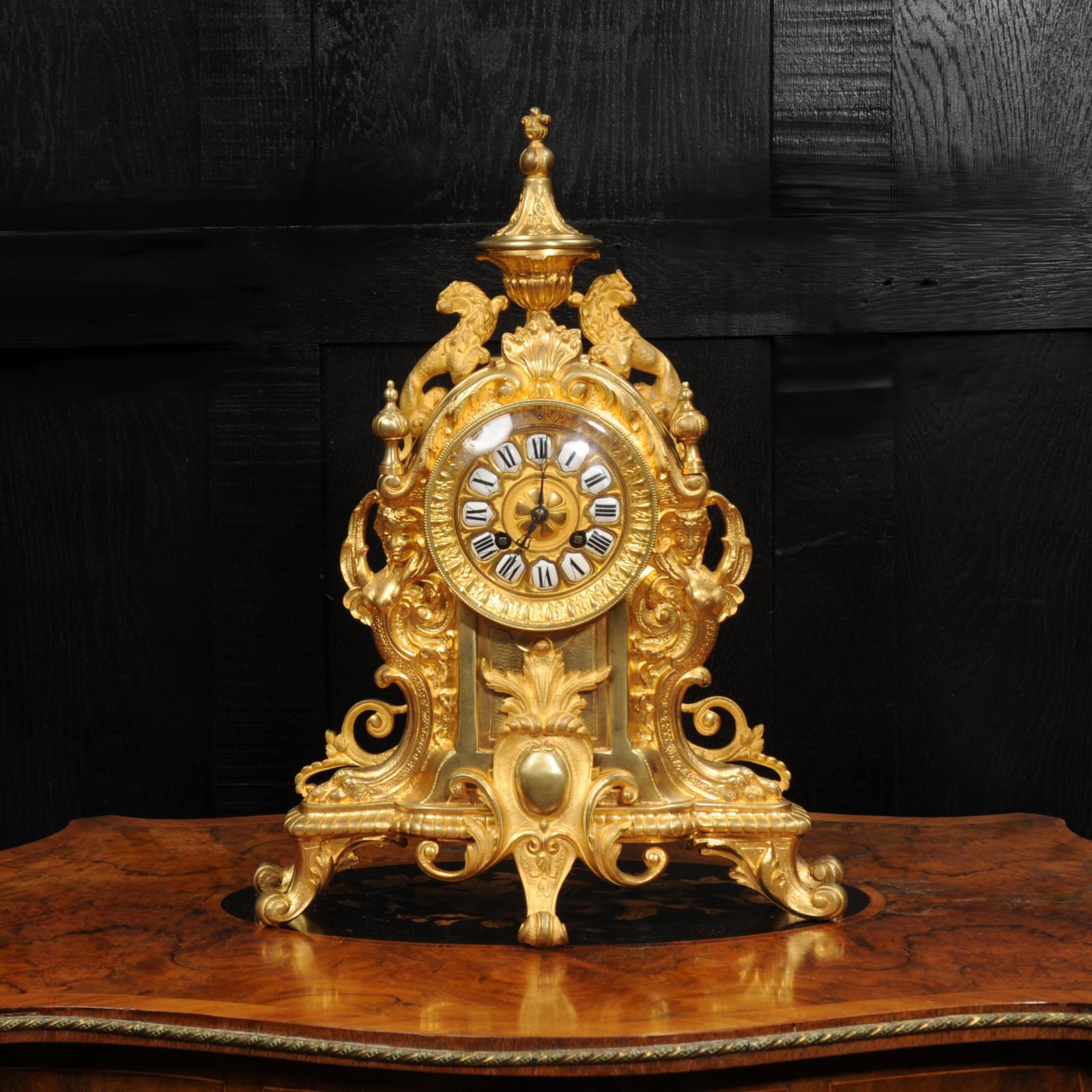 Une belle horloge française ancienne. Il est finement modelé en bronze doré et présente deux lions de chaque côté d'une urne au sommet. De chaque côté du cadran se trouvent d'exquises déesses ailées formées dans le flanc du boîtier. La dorure