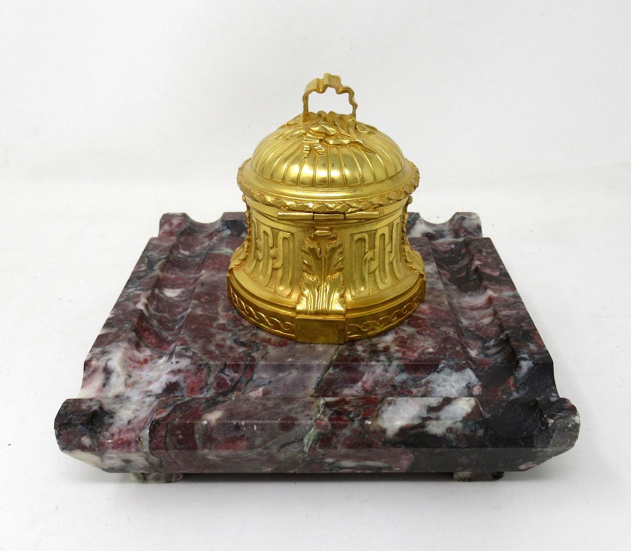 An exceptionally fine quality French heavy gauge ormolu bronze and well veined breche violette marble desk inkwell well of square outline, possible from the third quarter of the 19th century.

The central hinged lid and waisted bronze inkwell with