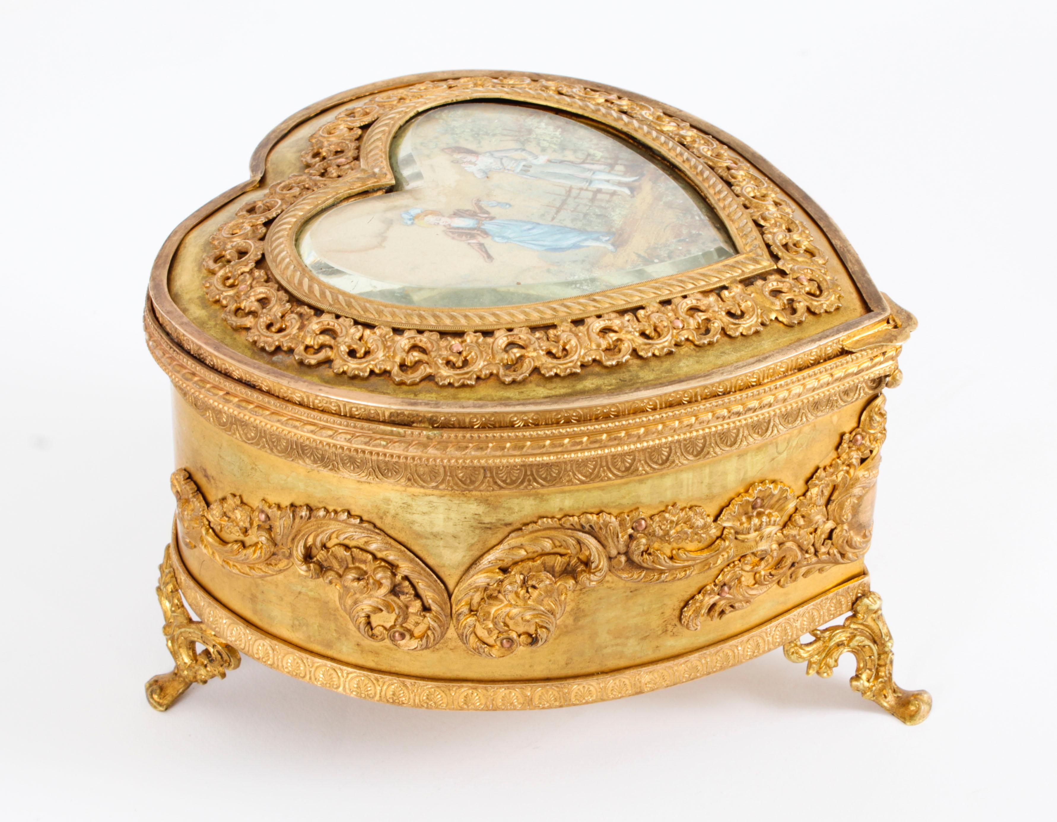 This is a beautiful Antique French heart shaped ormolu jewellery casket, circa 1880 in date.
 
Of heart form this wonderful casket is of very high quality and features a central bevelled glass covered panel of a miniature gouache on silk depicting