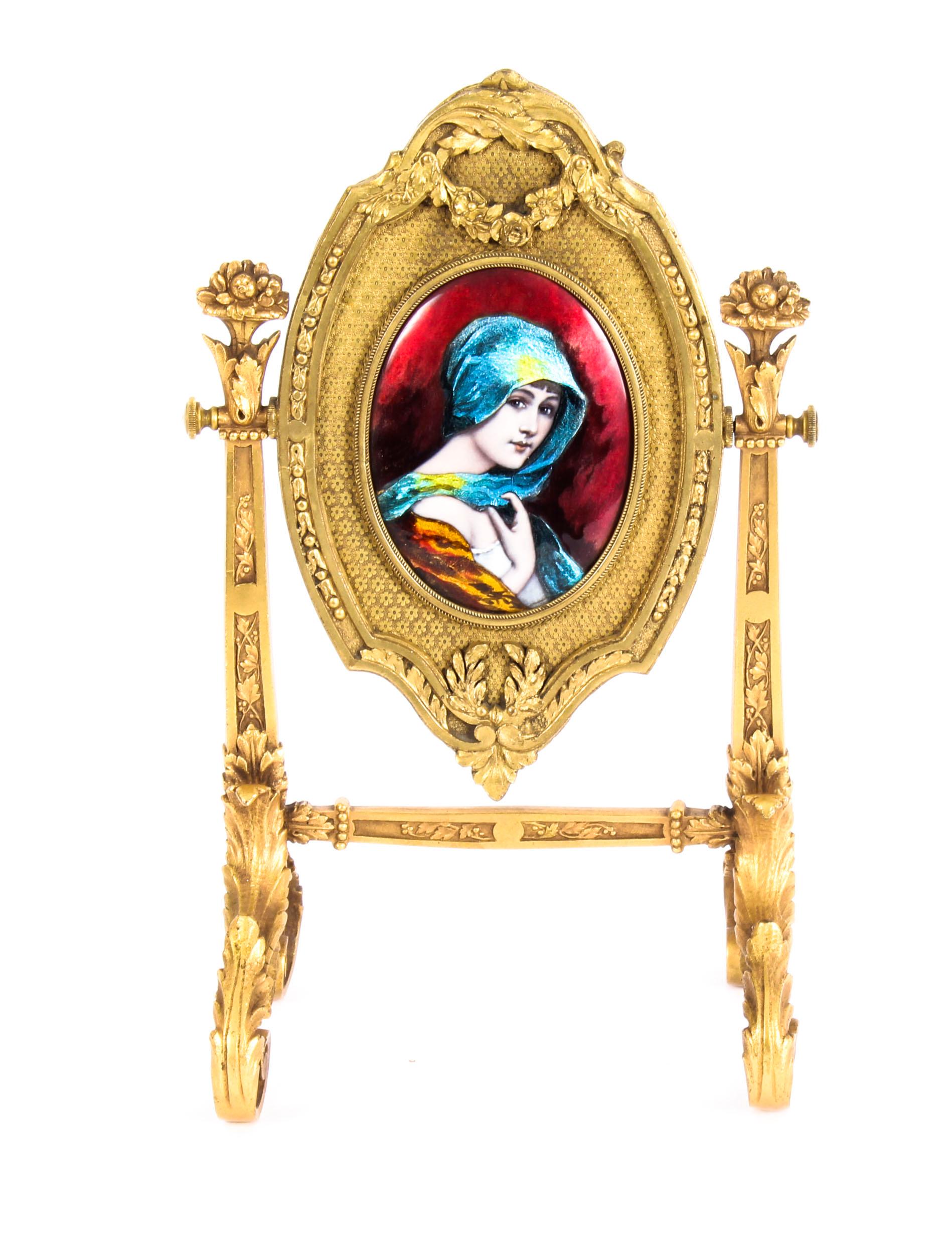 This is an impressive and highly decorative French gilt bronze and Limoges enamel table mirro, Signed, F.Bienvue, Limoges and circa 1880 in date.

The enameled portrait roundel on a floral ground with swag and acanthus leaves, fitted with a bevelled