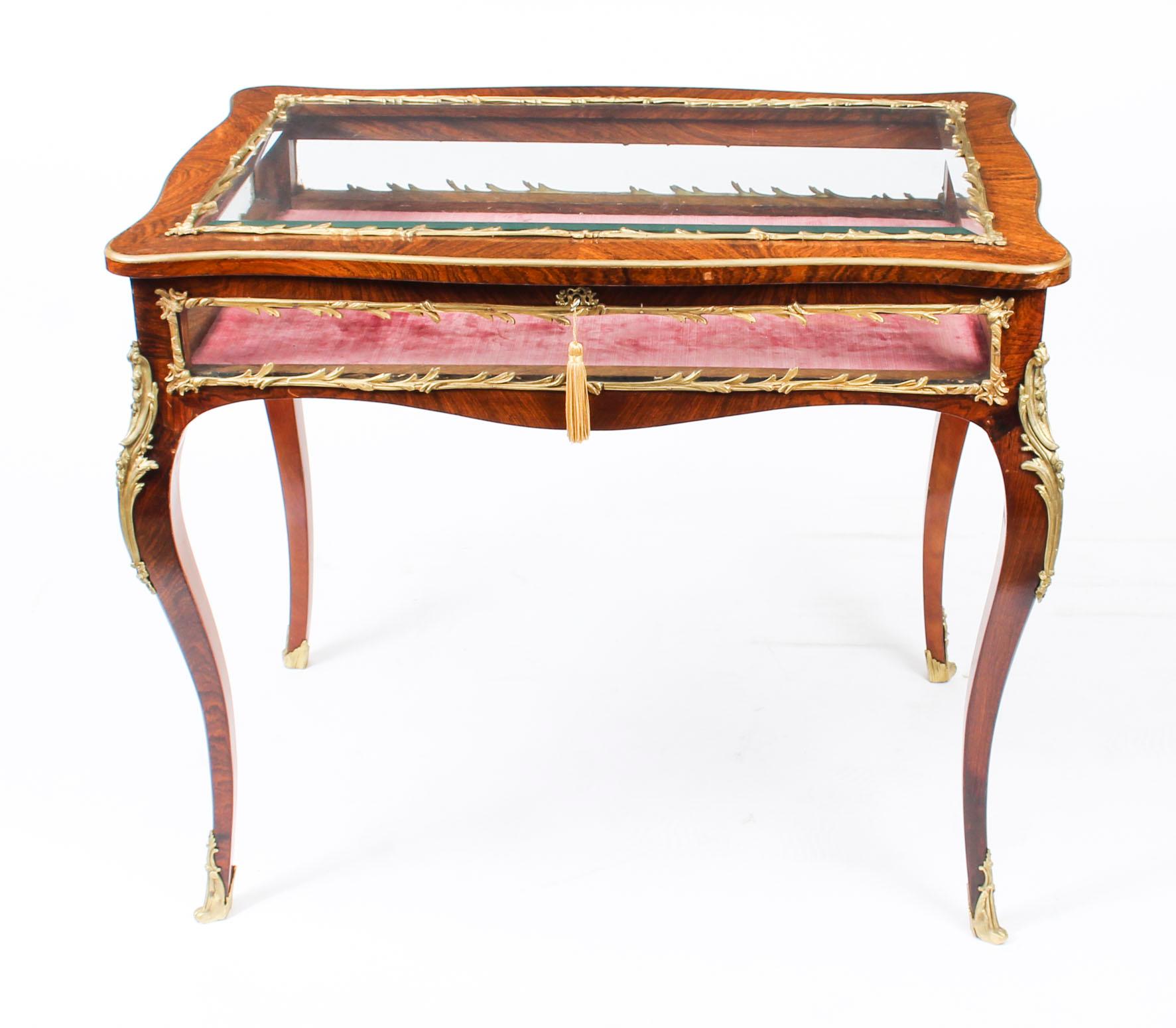 This is a beautiful antique French Gonçalo Alves and ormolu-mounted bijouterie display table in the Louis XV style, circa 1860 in date.

The display table features a bevelled glass top and glass sides, it has it's original pink velvet