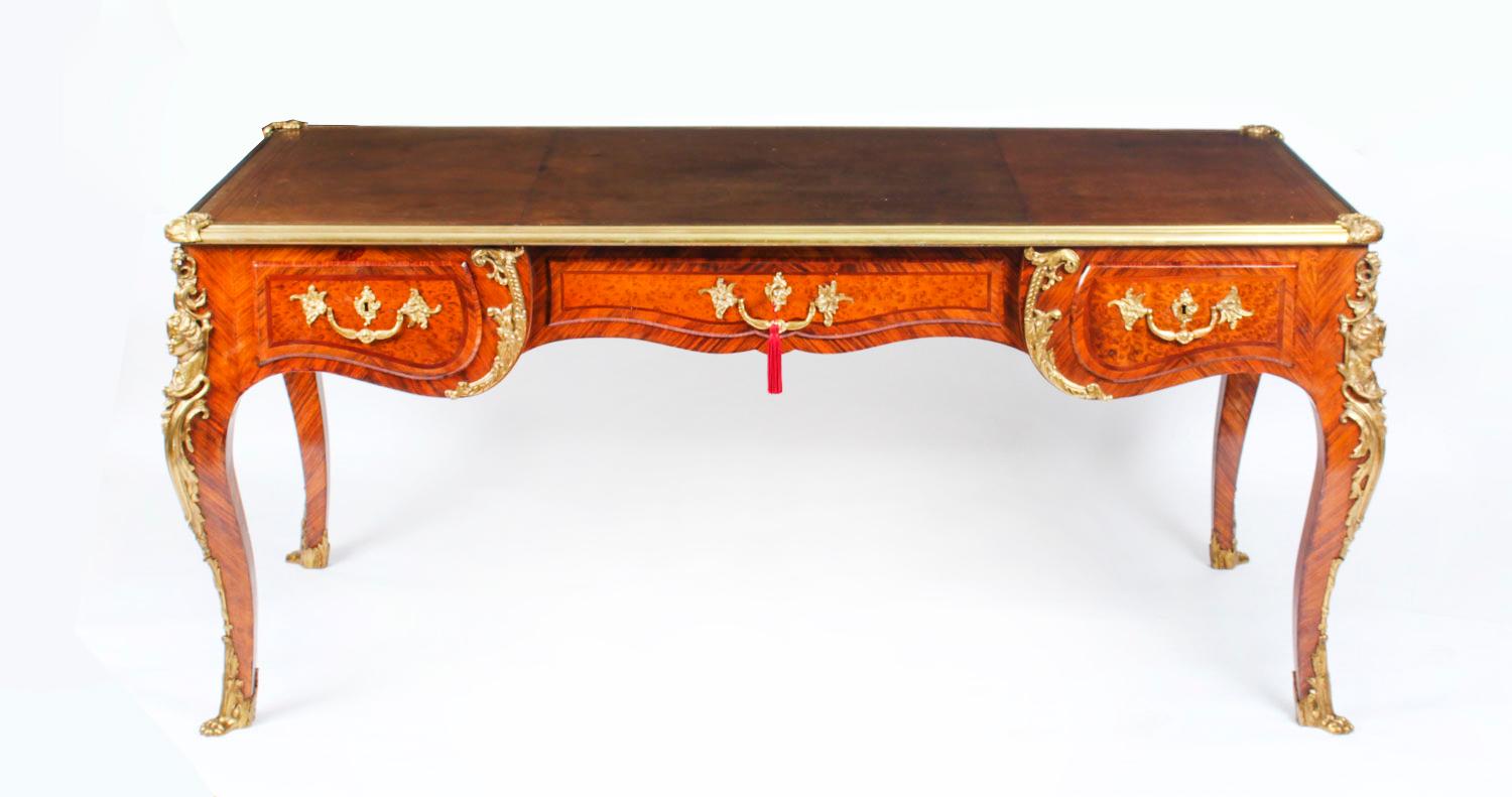 This is a fine and rare antique ormolu mounted French mahogany and amboyna bureau plat in the manner of Charles Cressent, Circa 1860 in date.
The shaped rectangular top has a decorative ormolu border and is inset with the original gilt-tooled tan