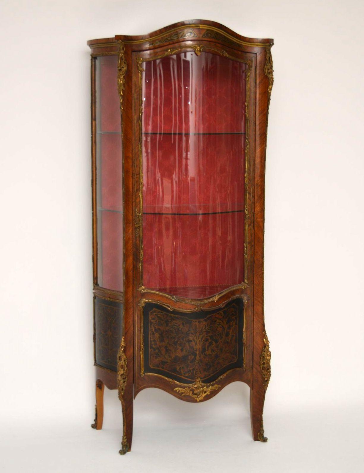Antique French display cabinet in either Kingwood or Rosewood, with brass inlays and faux boulle bottom panels. It's has a serpentine shaped front and the shaped glass on the front door and sides are original. This display cabinet is in lovely