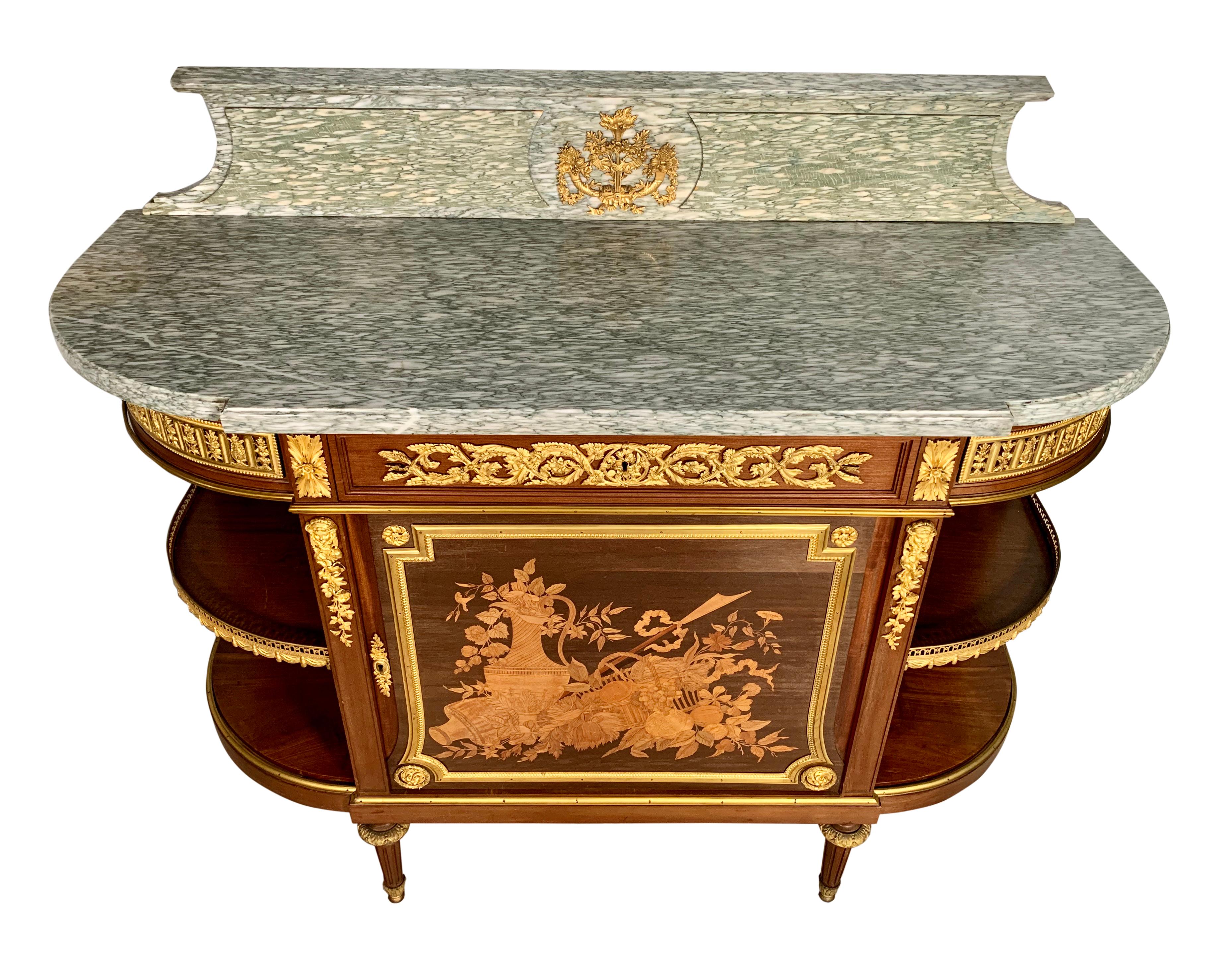 A high quality French ormolu-mounted mahogany, Amaranth and Marquetry marble top console Desserte - in the manner of Jean-Henri Riesener.
The D-shaped green Cippolino marble-top above a breakfront frieze centered with a drawer over a cupboard door