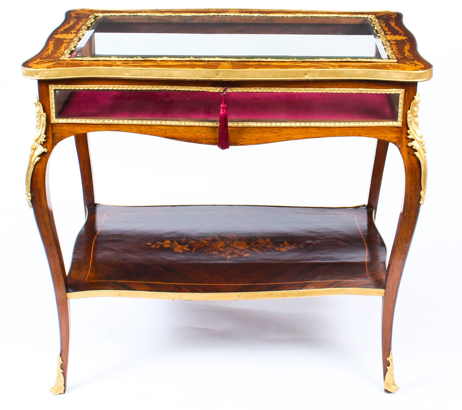 This is a truly wonderful large antique French Gonçalo Alves and ormolu-mounted Louis Revival bijouterie display table circa 1860 in date.

The display table features a hinged and shaped beveled glass top inlaid with harebells and acanthus leaves,