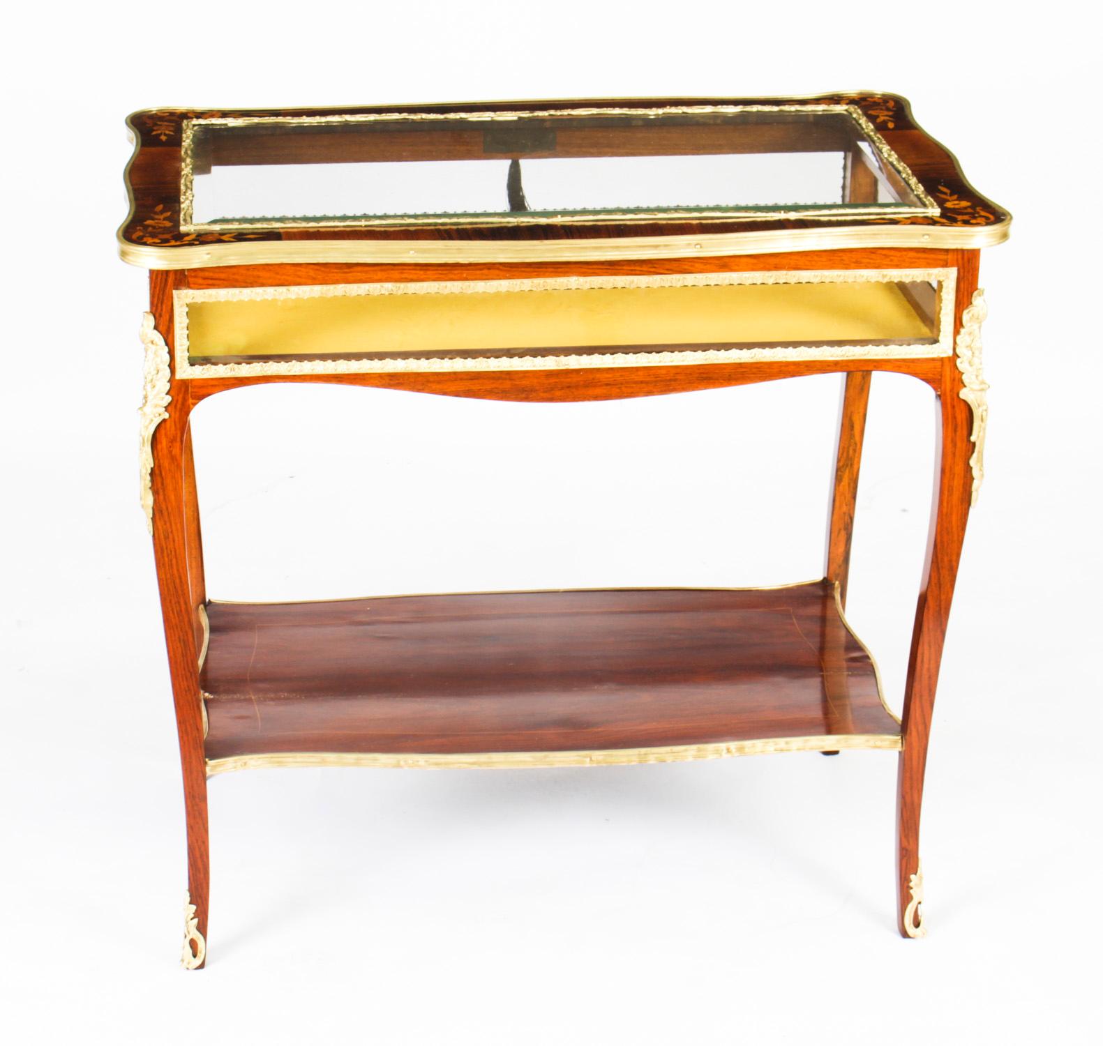This is a truly beautiful antique French marquetry and ormolu mounted Louis Revival bijouterie display table circa 1860 in date.
 
The display table features a hinged and bevelled glass top with serpentine ormolu edging, inlaid with floral