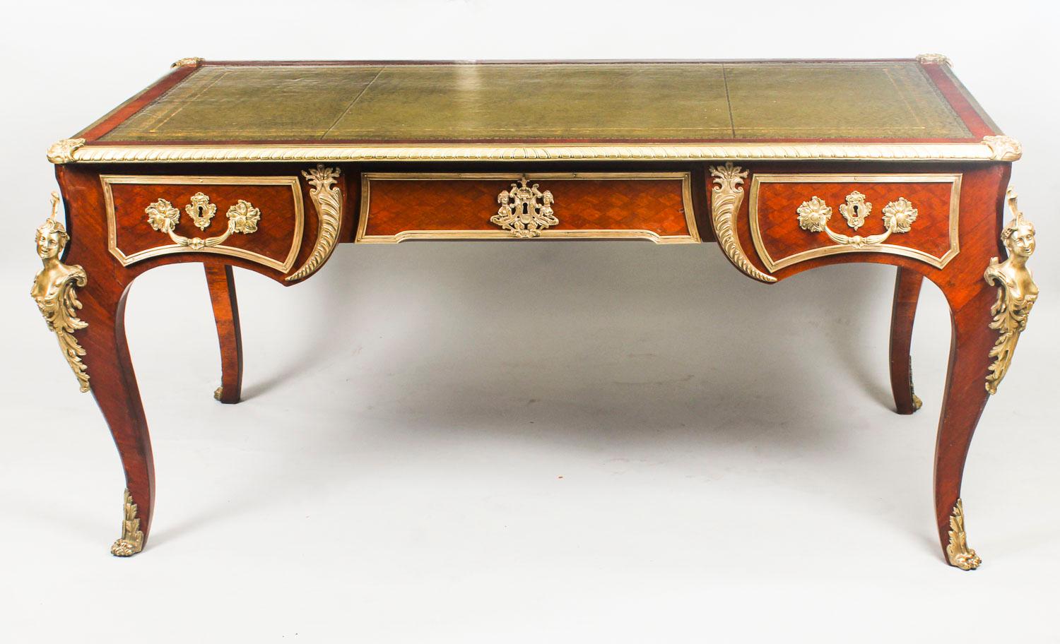 This is a gorgeous antique French Louis XV Revival mahogany bureau plat with highly decorative ormolu mounts, circa 1880 in date.

The rectangular top with a decorative gilt bronze border, raised corner cartouches and an inset gold tooled green