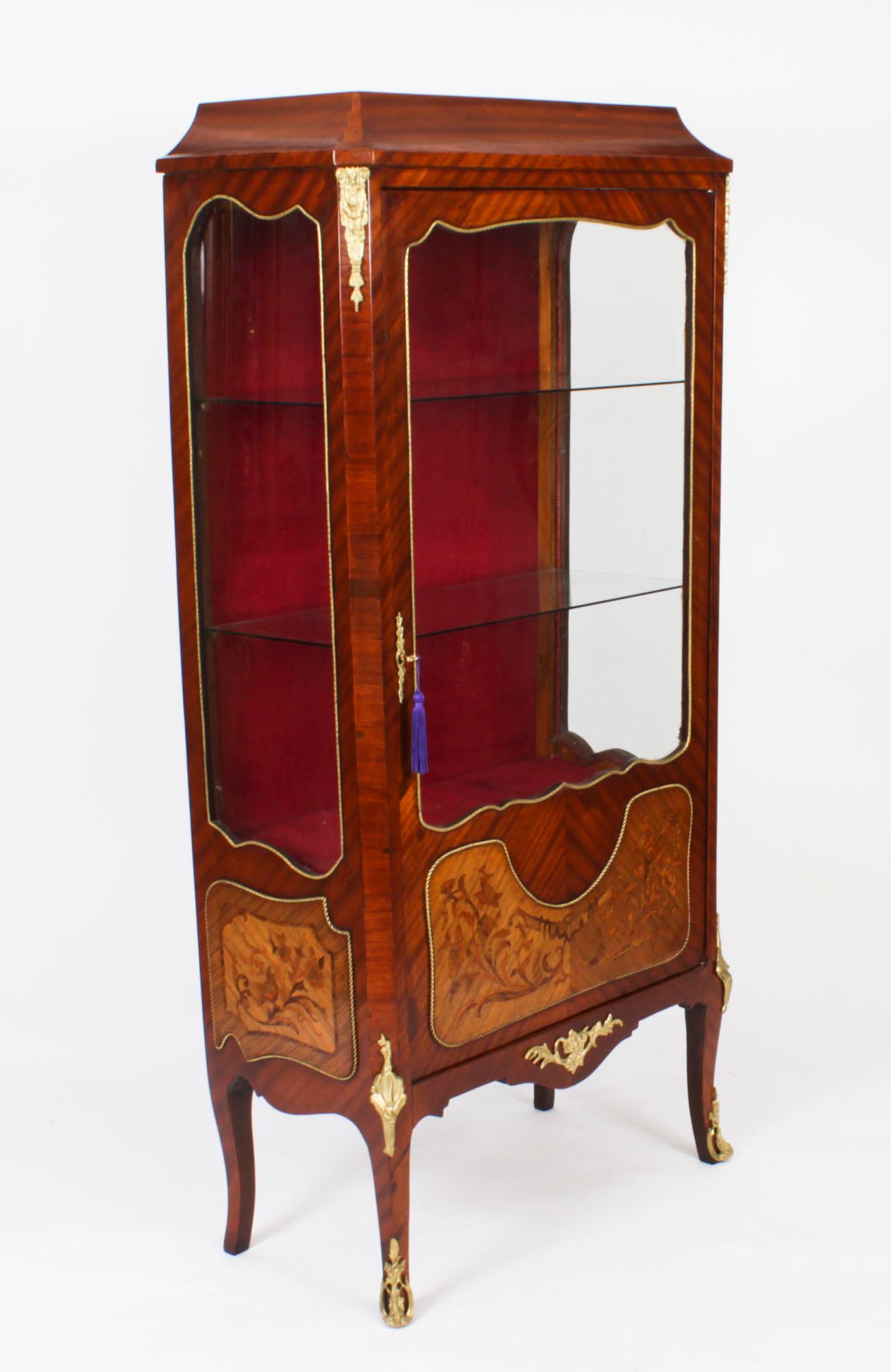 This is a stunning antique French Louis Revival ormolu mounted walnut and marquetry inlaid display cabinet, circa 1920 in date.

The cabinet features a shaped top and has impressive and ornate ormolu mounts. The body is rectangular shaped with a