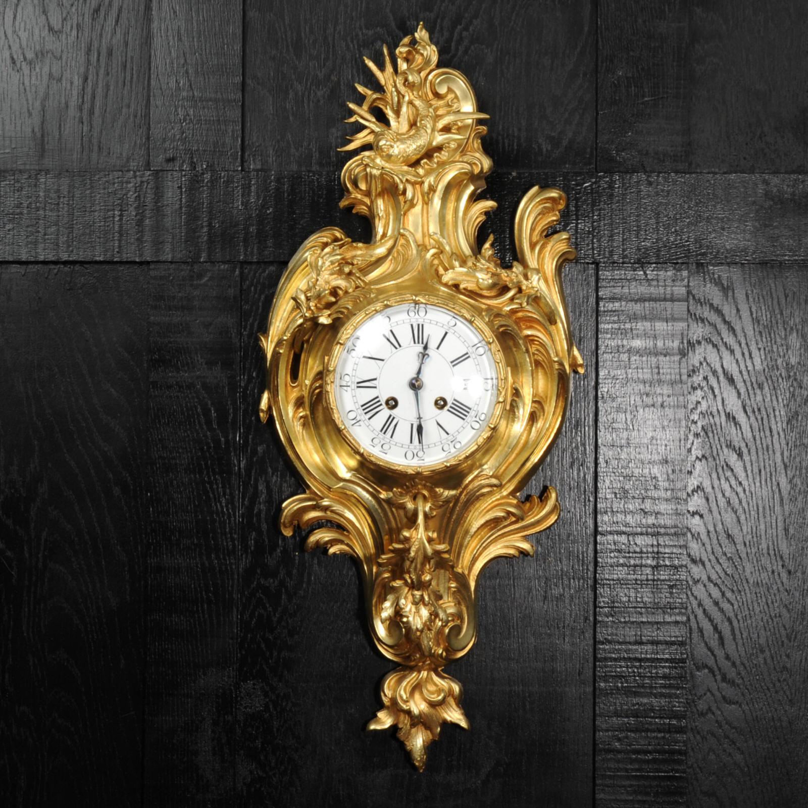 A beautiful original antique French cartel wall clock, circa 1880. It is finely made in ormolu (finely gilded bronze doré), in the Rococo style, and features a dolphin to the top, riding a C scroll of surf. The case is formed of flowing splashes of