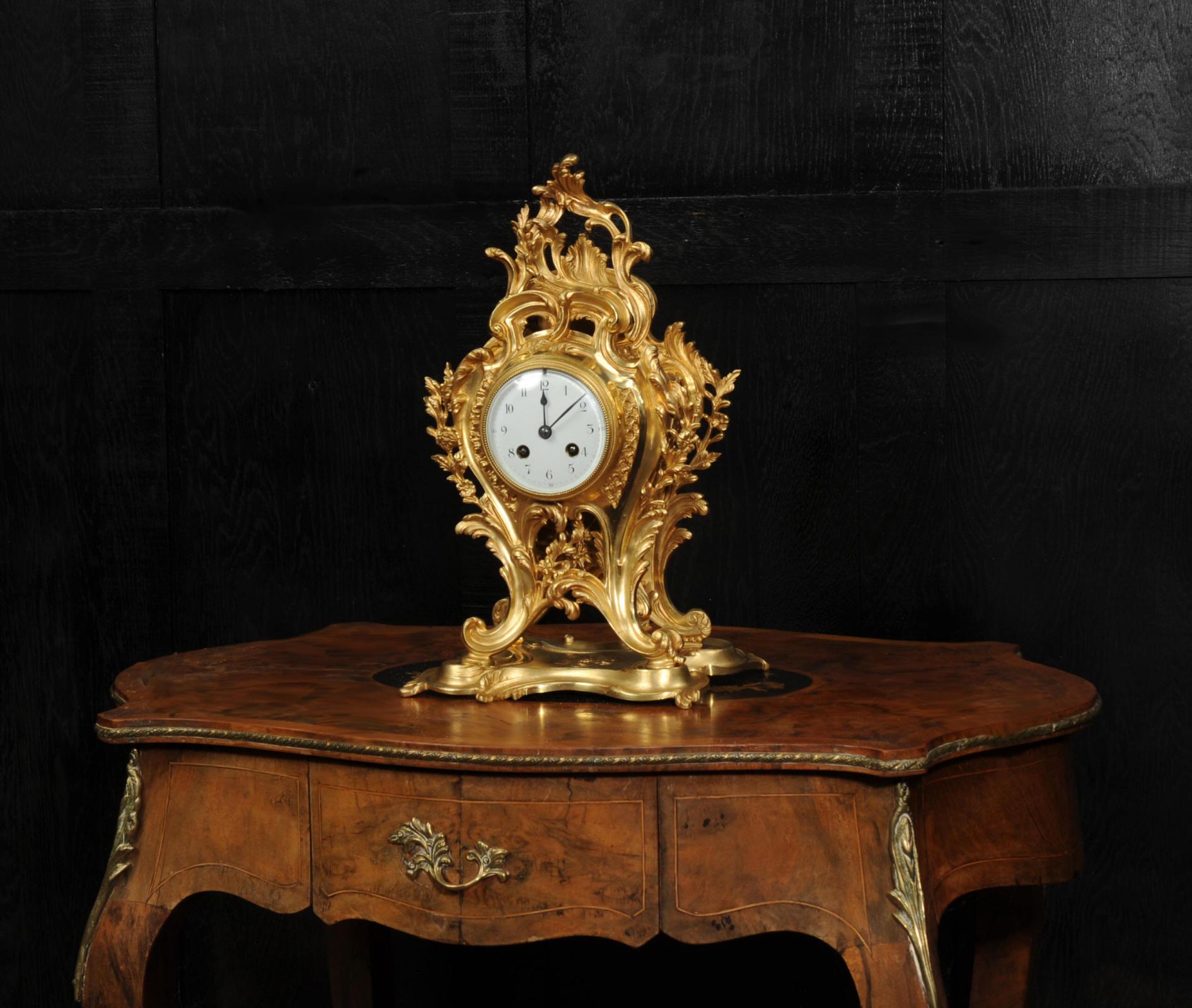 Eine herrliche originale antike französische Rokoko-Uhr. Geformt aus gewundenen Blattkurven mit floralem Blattwerk, alles in fein vergoldeter Bronze. Die Uhr steht auf einem formschönen Sockel. Durch die Öffnung auf der Vorderseite des Gehäuses kann