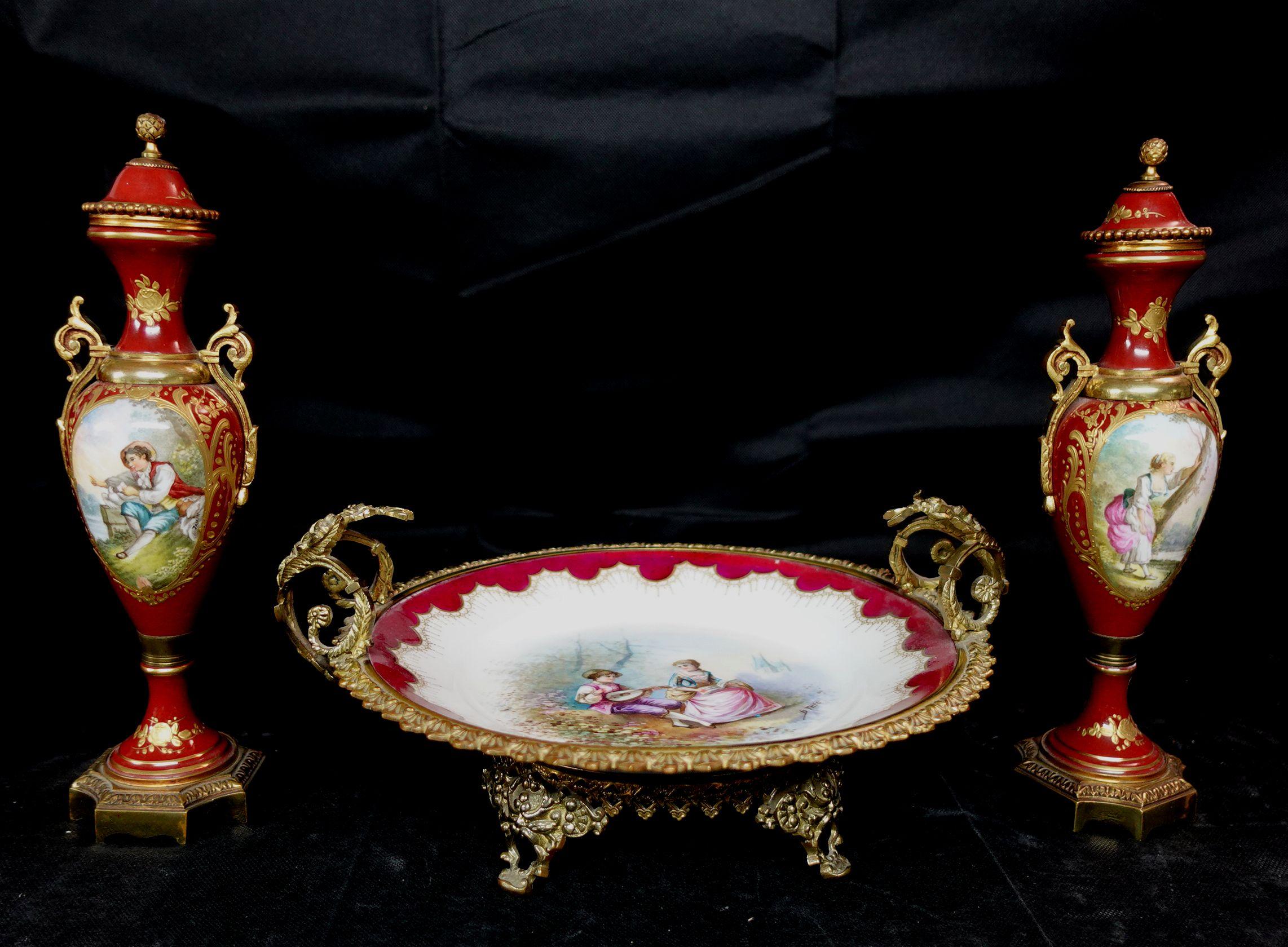 Antique French Ormolu Sevres style Garniture, 19th Century, Signature and Mark, Comprising an assembled garniture set consisting of two bolted urns with hand-painted scenes of lovers in a landscape, artist signed Jamin. Together with an