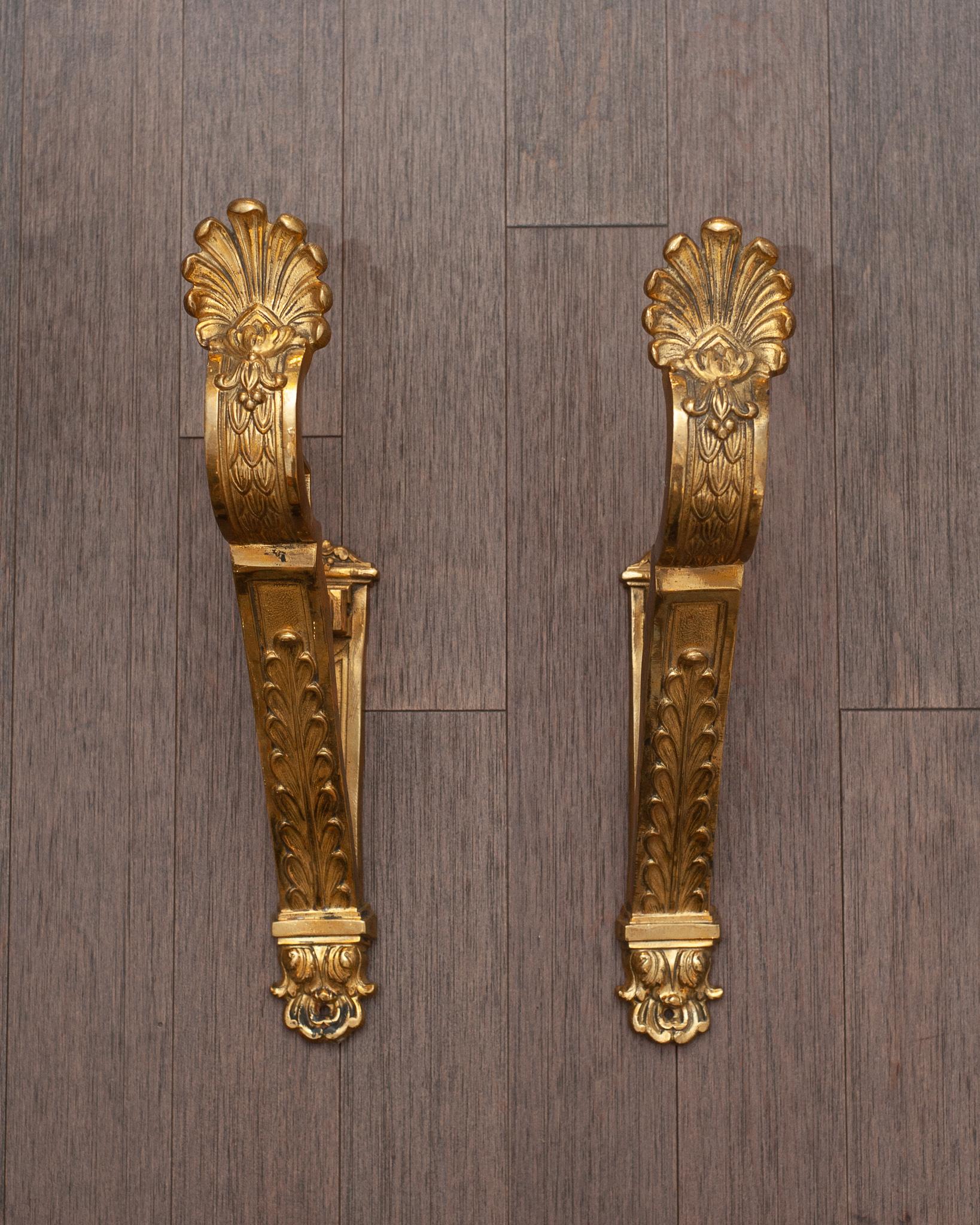 An antique French pair of sculpted gilt bronze curtain hooks or tie-backs richly decorated with foliage and shell motifs.