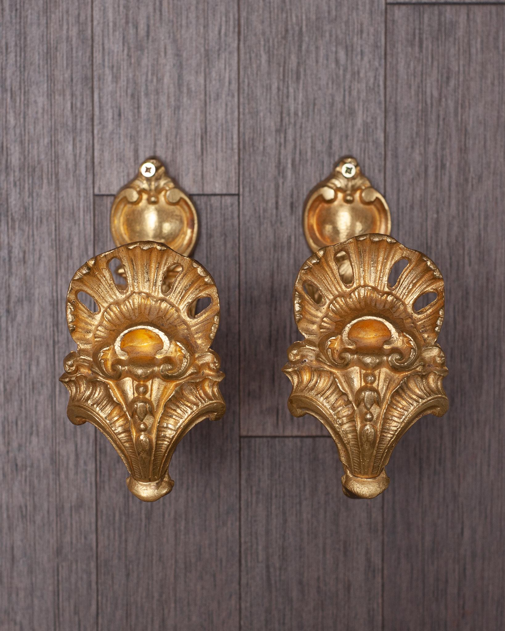 An antique French pair of sculpted gilt bronze curtain hooks or tie-backs richly decorated with shell motifs.