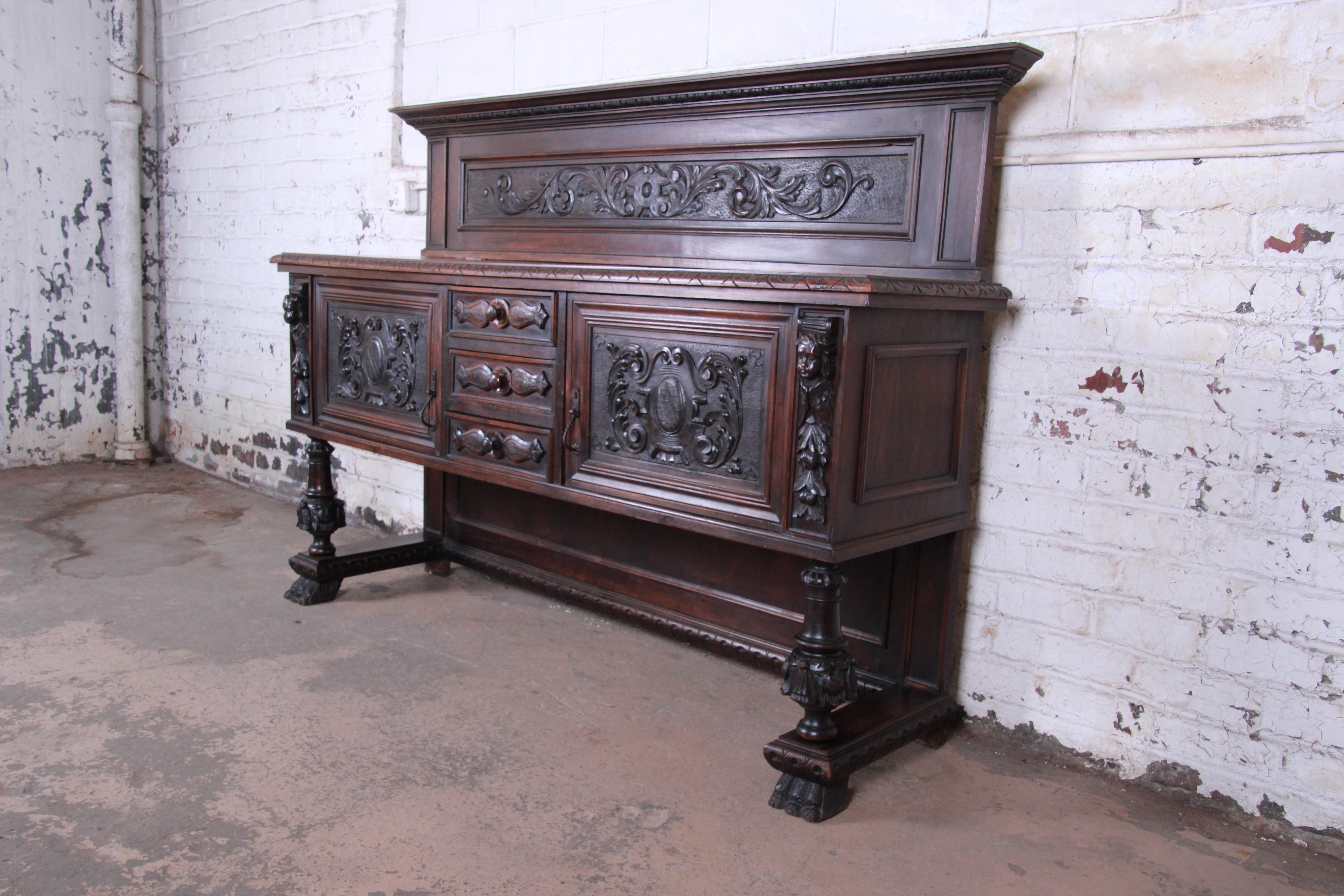 An outstanding 19th century French ornate carved walnut sideboard or bar cabinet. This outstanding cabinet features solid dark walnut construction with incredible carved wood details, including carved faces and paw feet. It offers ample storage,