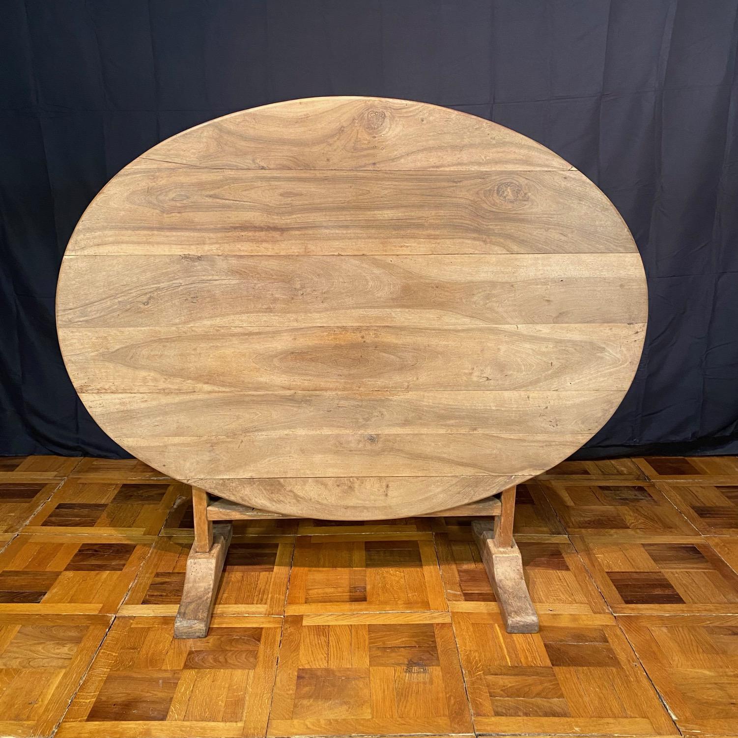Table de vendange ancienne en noyer, vers la fin des années 1800. Plateau ovale sculpté sur une base à tréteaux avec mécanisme de harpe triangulaire. Pieds arrondis et sculptés à la main. Tilt-top entièrement fonctionnel et pouvant être stocké