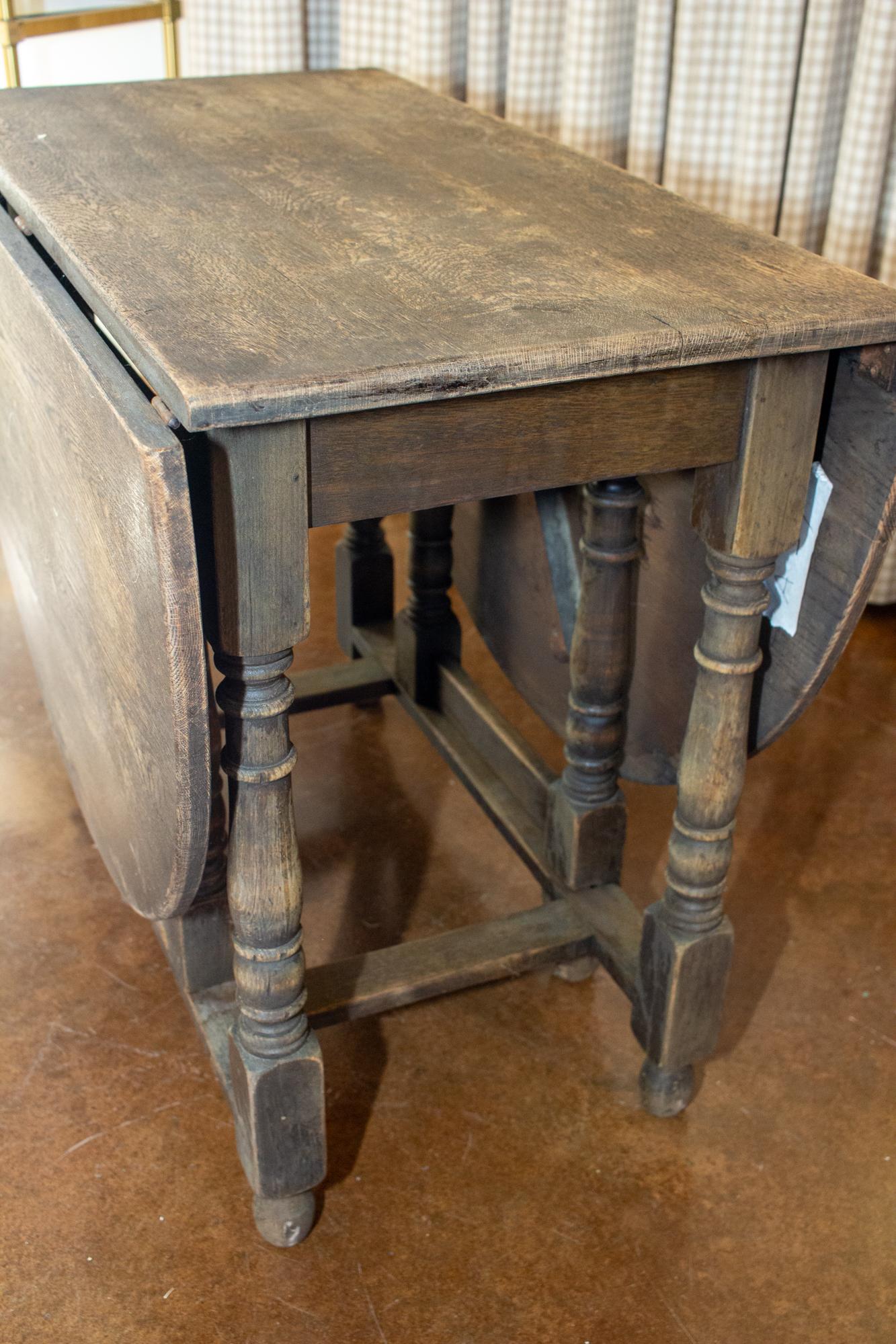 Questo antico tavolo francese in legno di quercia intagliato a mano è dotato di foglie a scomparsa su entrambi i lati e presenta dettagli di gambe tornite. La finitura marrone intenso è probabilmente originale e questo pezzo può essere utilizzato