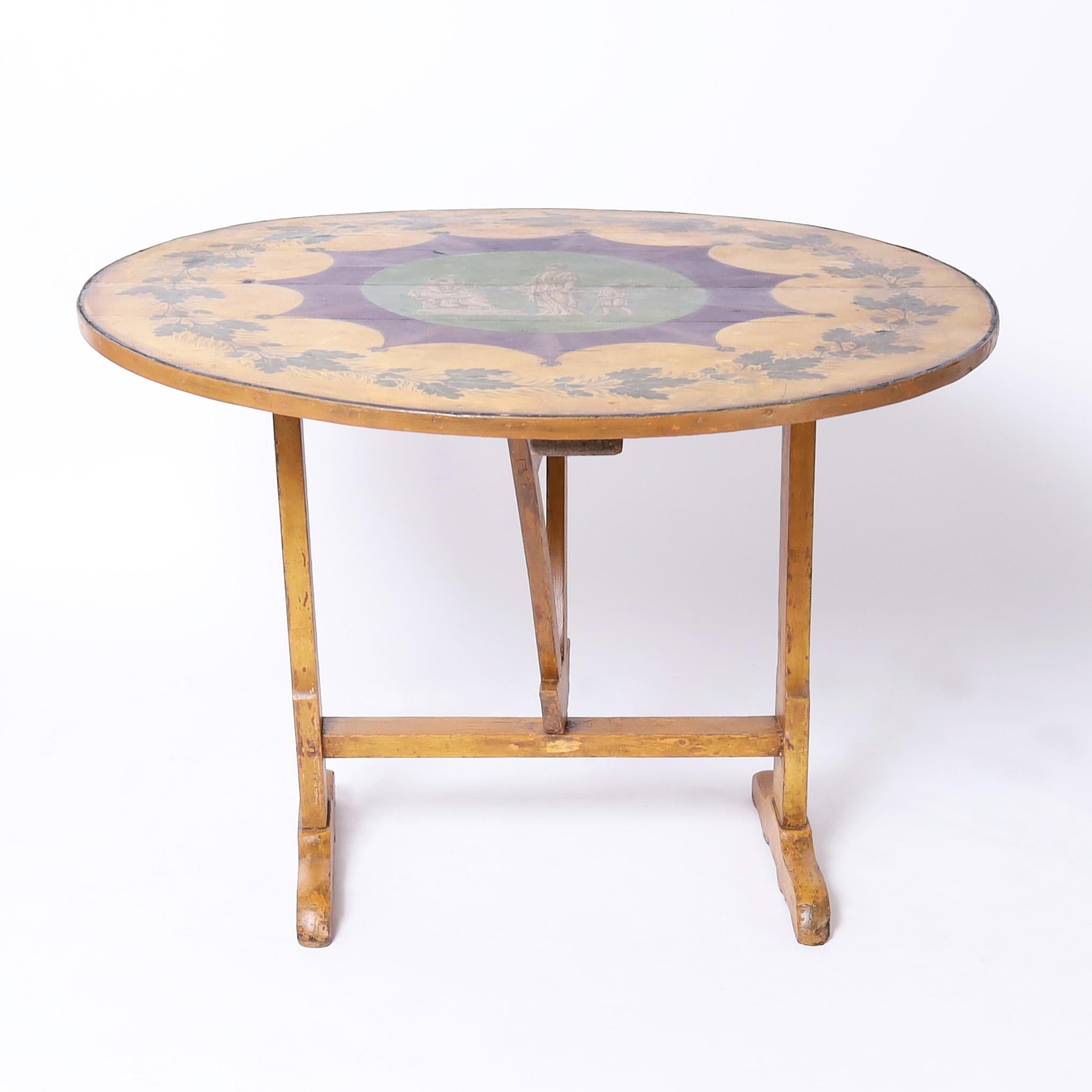 Impressive 19th century French wine tasting table hand crafted in walnut with a tilt top paint decorated with leaves and acorns around a center medallion with classical figures on painted trestle base with butterfly wedge supports.

H: 28 DM: