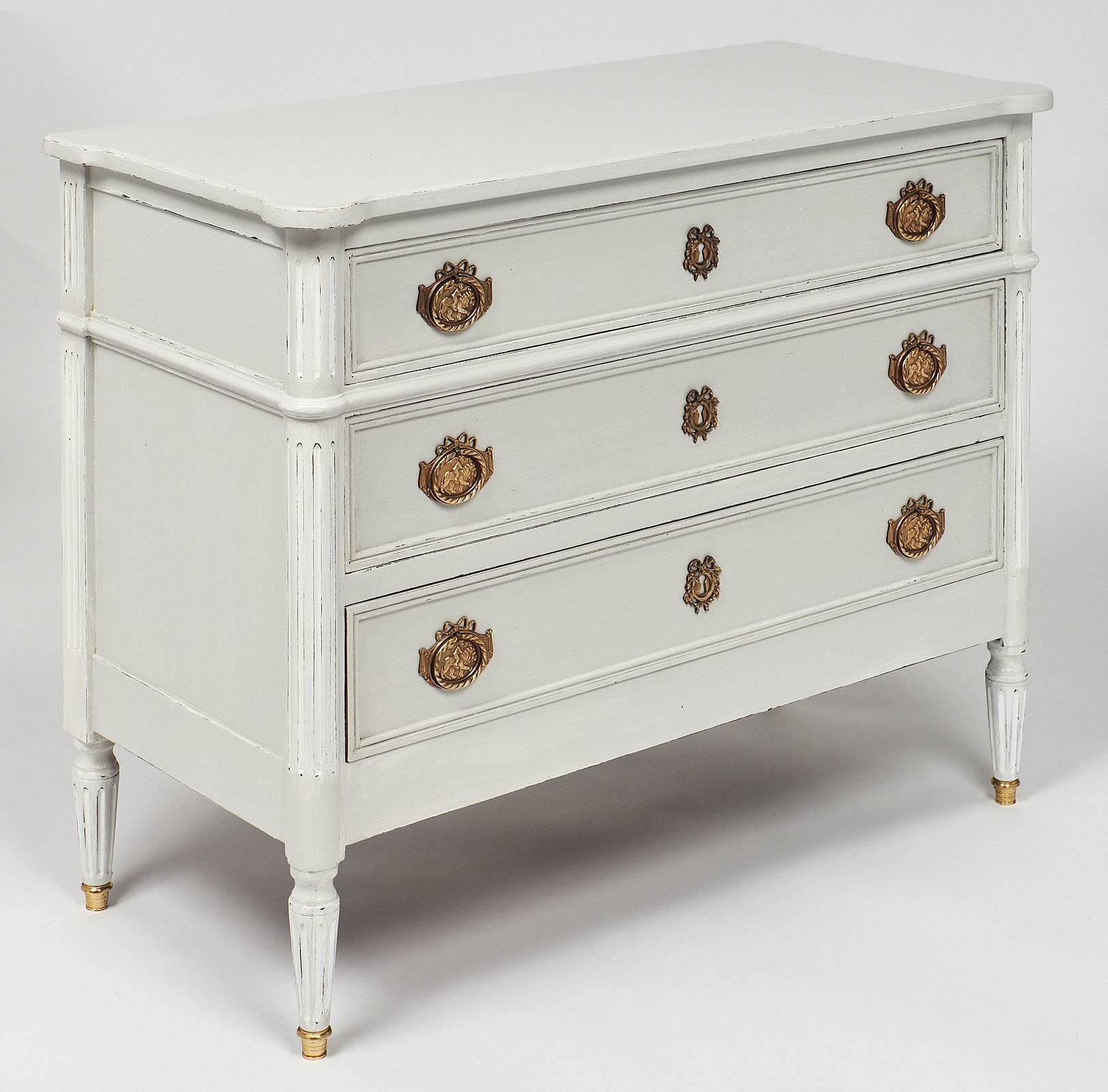 French painted antique French chest of drawers made of cherrywood with an elegant two tone milk paint patinated finish and hand-carved fluted details. The chest has three dovetailed drawers that open up to a comfortable amount of storing space.