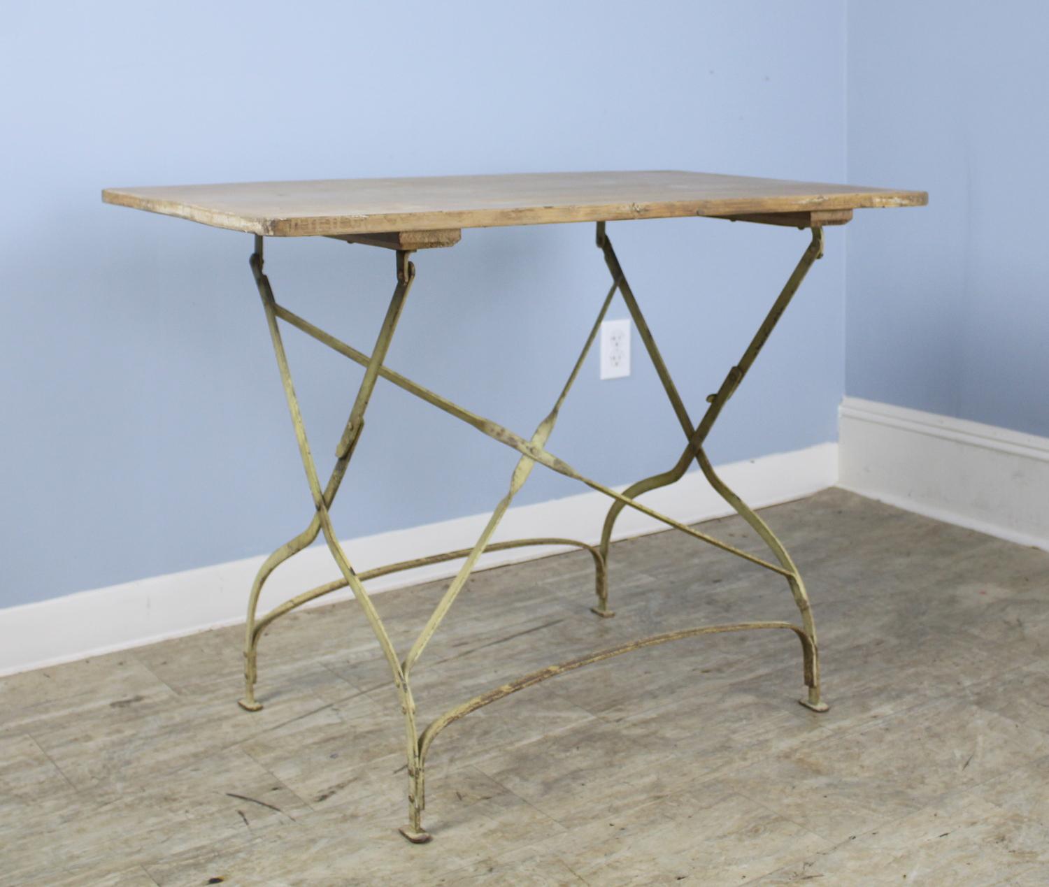 A charming French folding picnic table with a washed back wooden top and good wrought iron legs. The paint on the top is refreshed and clean, and the piece opens and closes easily, standing upright on its own when folded.