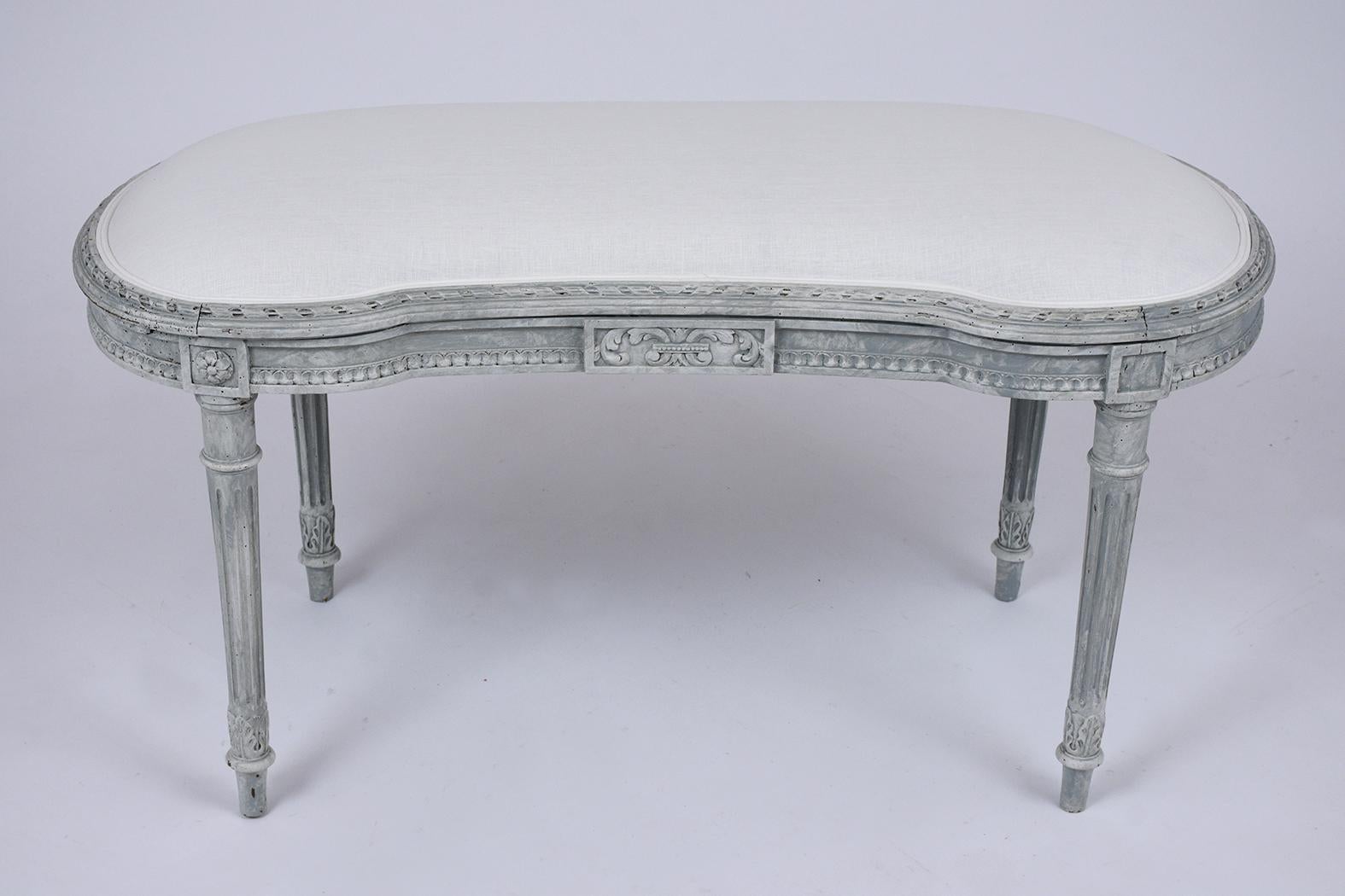 This antique French Louis XVI bench is made out of walnut wood and has been completely restored by our team of expert craftsmen. This late 19th-century bench features a kidney shape frame with finely hand-carved details, a new hand-painted pale gray