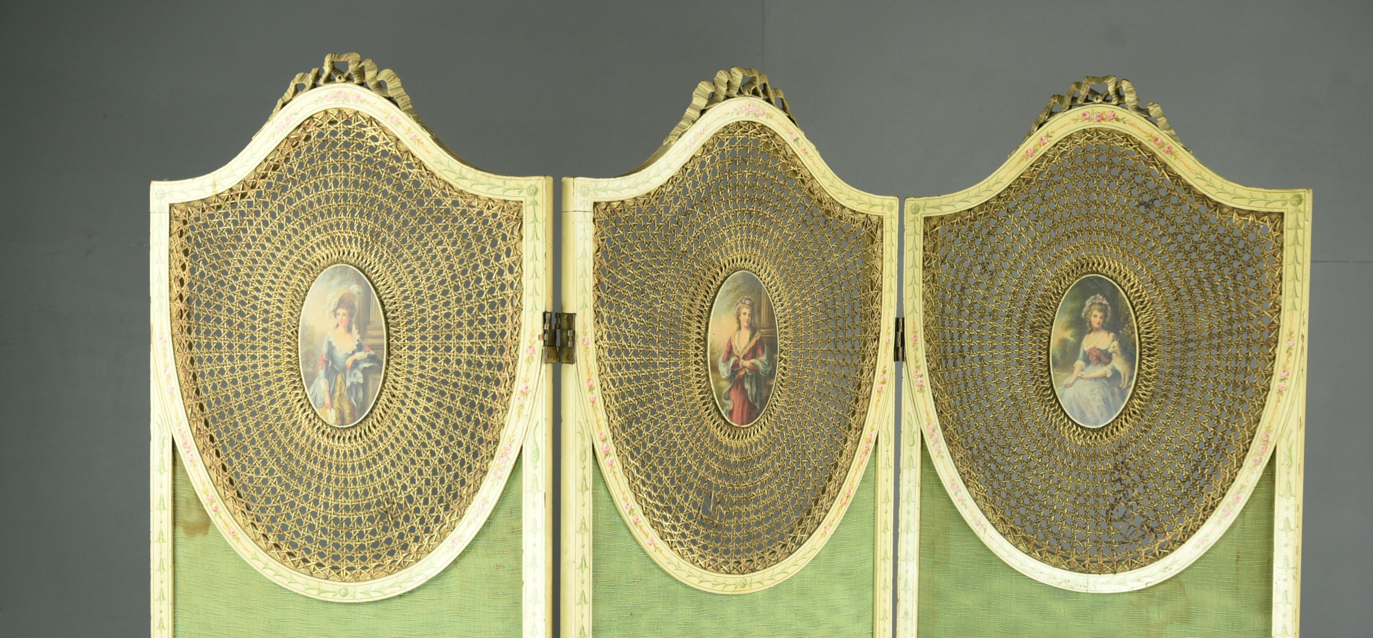 Decorative painted three fold screen with shield shape caned panels each with hand painted oval portraits of ladies in period costume The tops with fine carved ribbon detail 137cm wide each panel being 47cm wide 180 cm high.
The screen is all