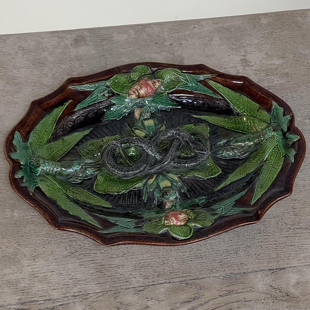 Antique French Palissy Majolica serving platter is an exquisite example of the genre, very well preserved and resplendent with jewel tones on a rich background creating a very decorative effect. Resting upon various aquatic and water-loving plants,