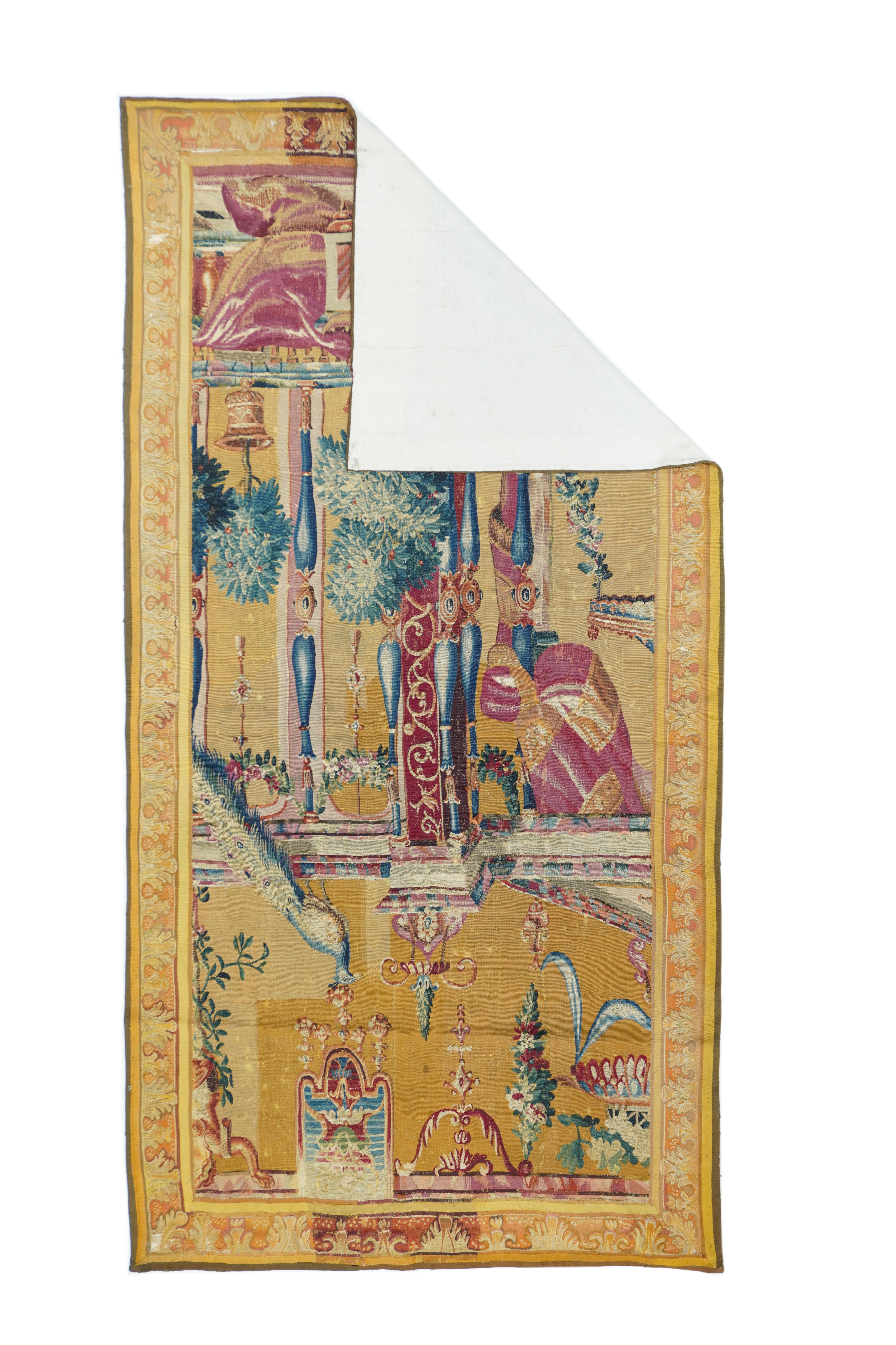 This is a vertical fragment of a “Berain” Grotesque tapestry with performers in front of an architectural backdrop of columns, architraves, cloth drapes, floral swags and potted plants, on a salmon-tan ground. Multiple secondary shades of red, blue,