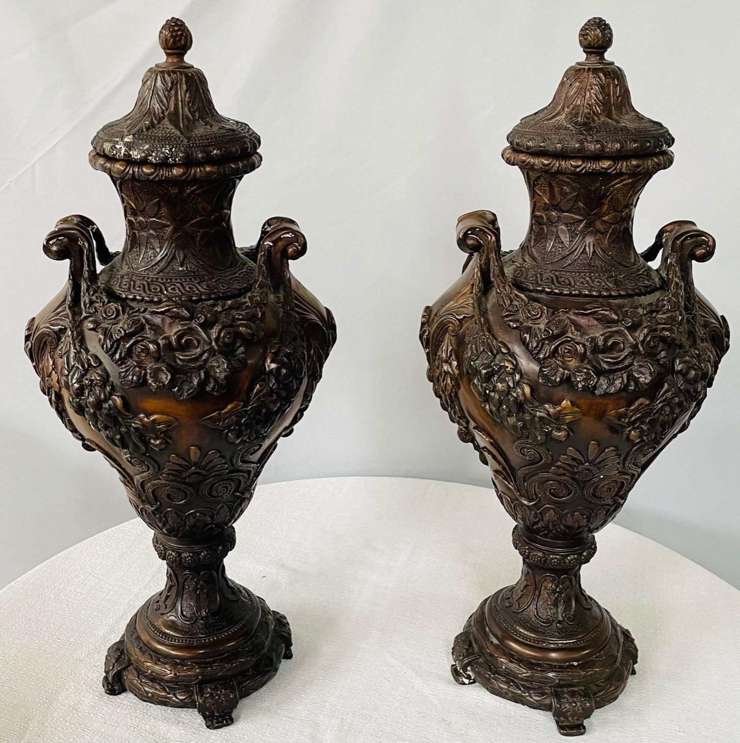 A pair of 19th century French patinated bronze urns featuring floral motifs. Throughout the pieces. The urns can be used as painters by removing the final cap. In a patinated finish, the pair of bronze urns will add sophistication and elegance to