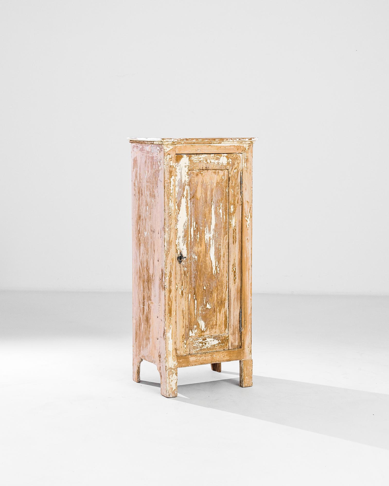 A patinated wood cabinet from France, produced circa 1900. A small cabinet streaked with remnants of white patination across the facade, top and three other faces, featuring a locking door containing a space with three shelves. This cabinet’s