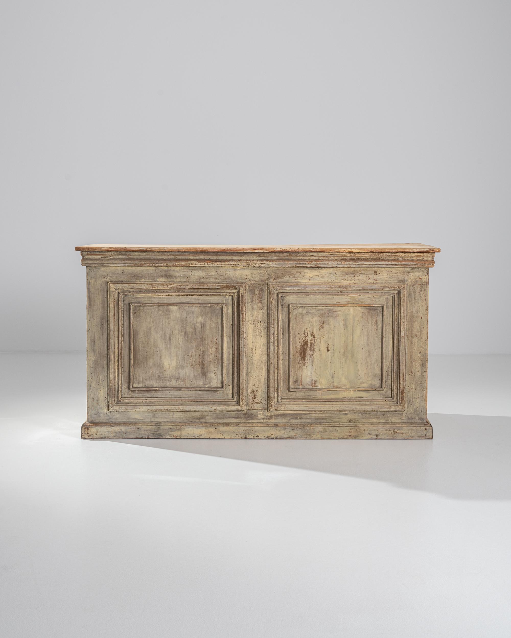 This antique wooden bar was once an elegant fixture in a bistro or restaurant. Made in France in the 1800s, the clean yet elegant composition evokes the shape of a classical plinth: the decorative details of the right-angled paneling and carved