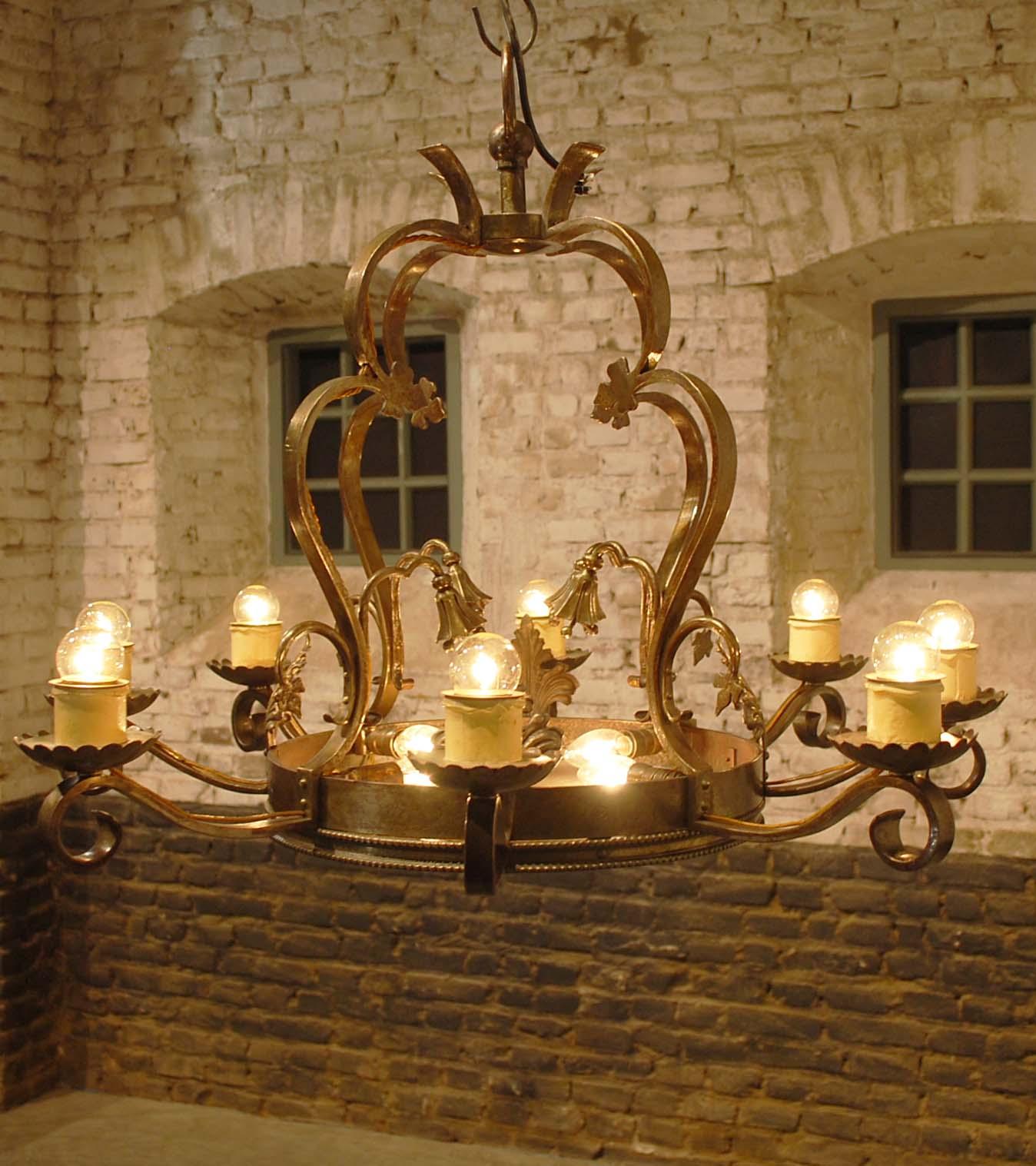 This unique chandelier was hand forged by a master blacksmith.
It features 8 arms each equipped with an E27 fitting with a cardboard candle.
The whole chandelier was forged in pieces and riveted together. It is decorated with acanthus, fleur de