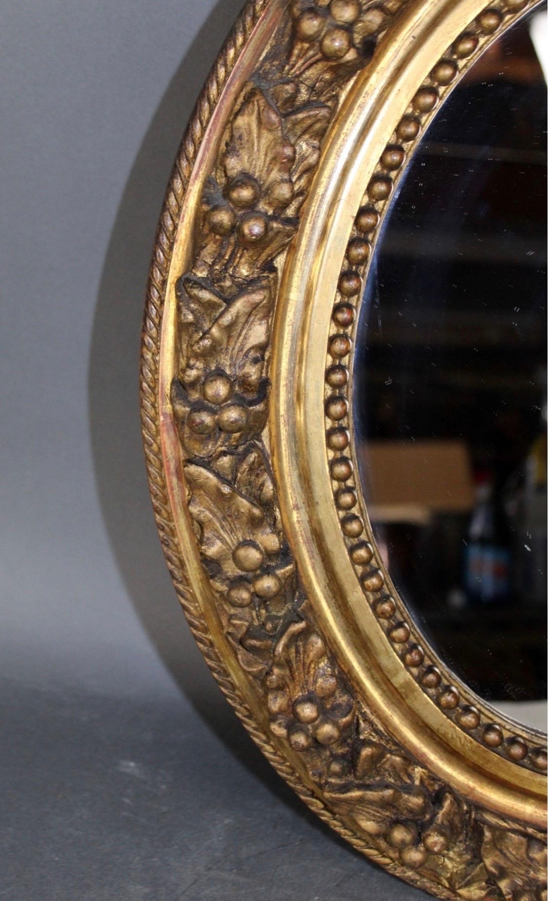 Antique French Petite Giltwood Oval Mirror with Relief Carved Grape Vine Foliage Decoration is Early 20th Century.

 Mirror deminsions are approximately 18 5/8
