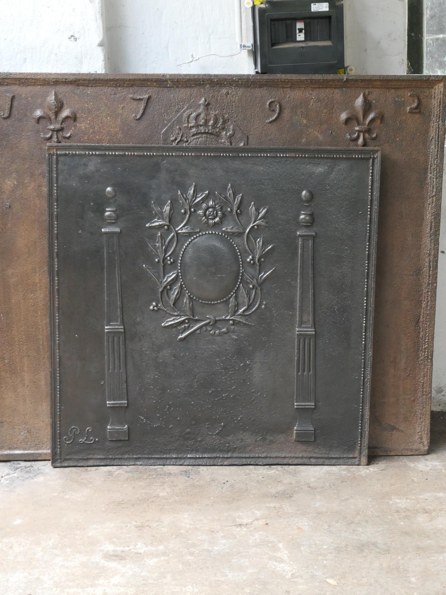 18th - 19th century French neoclassical fireback with two pillars of freedom and a floral decoration. The pillars symbolize the value liberty, one of the three values of the French revolution. 

The fireback is made of cast iron and has a natural