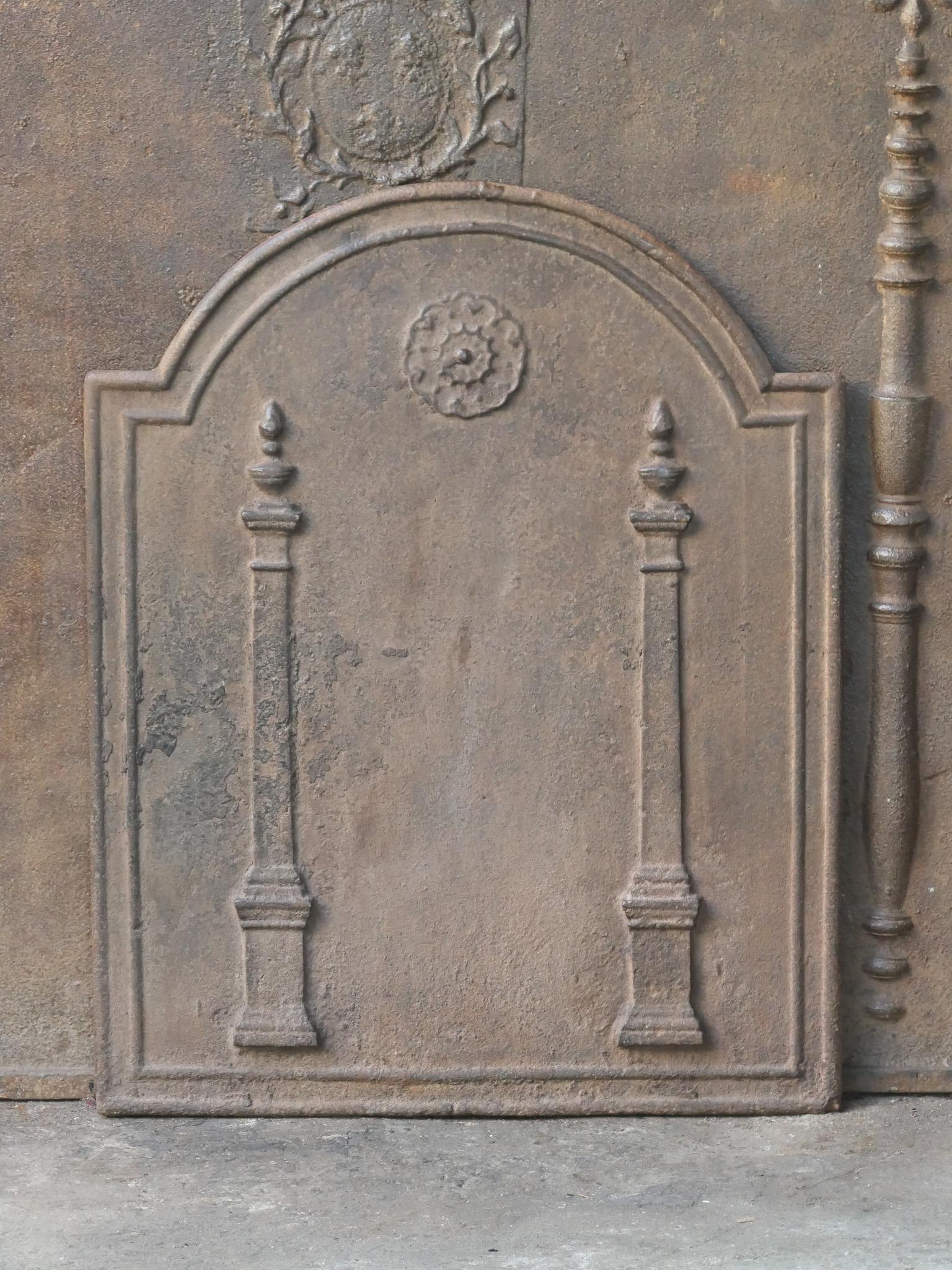 18th - 19th century French neoclassical period fireback with two pillars of freedom. The pillars symbolize the value liberty, one of the three values of the French revolution. 

The fireback is made of cast iron and has a natural brown patina. Upon