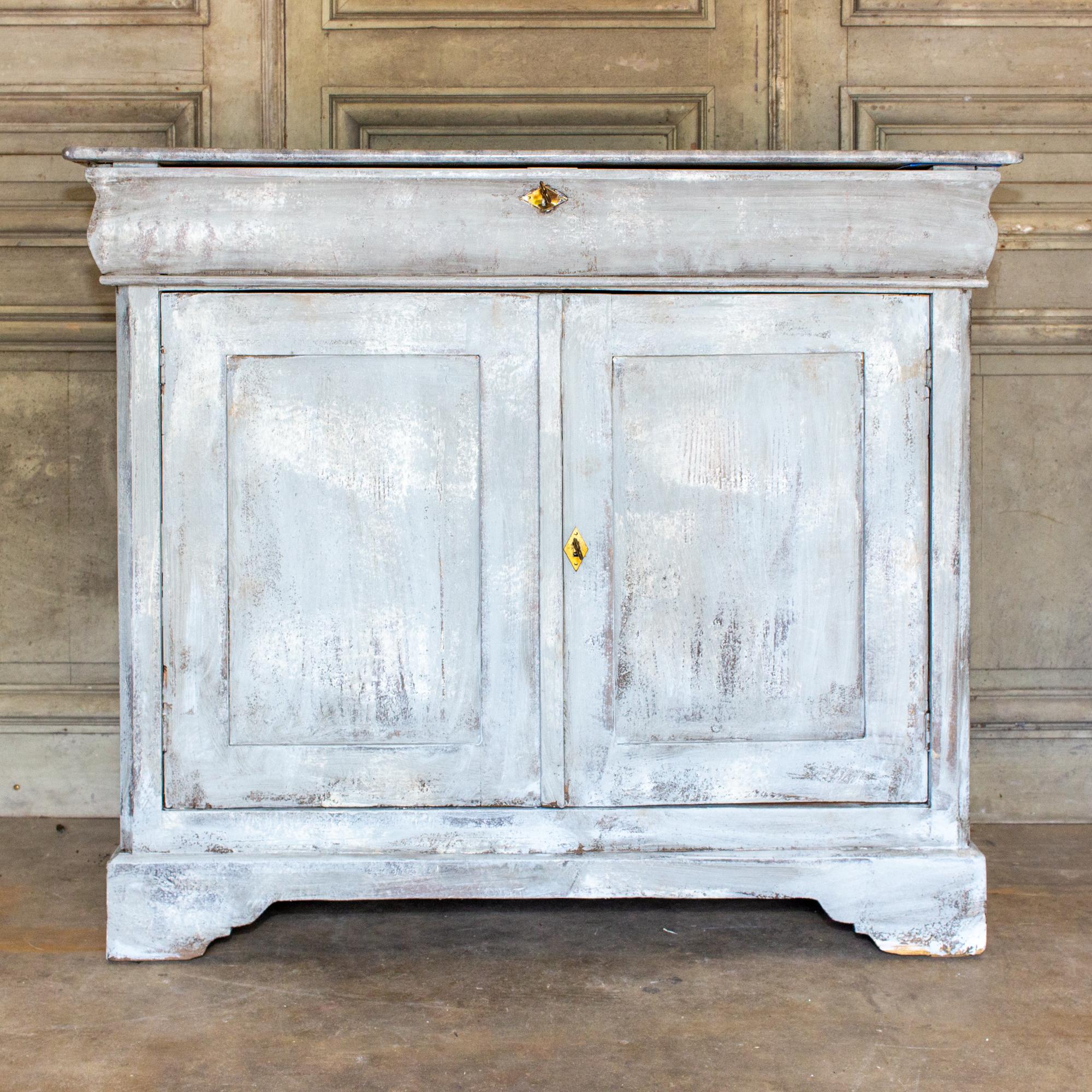 This antique French pine buffet has been given new life with an expertly hand-painted and distressed greige finish. The top has been painted to mimic the stone and has a higher gloss finish than the body of the cabinet. The top drawer features a key