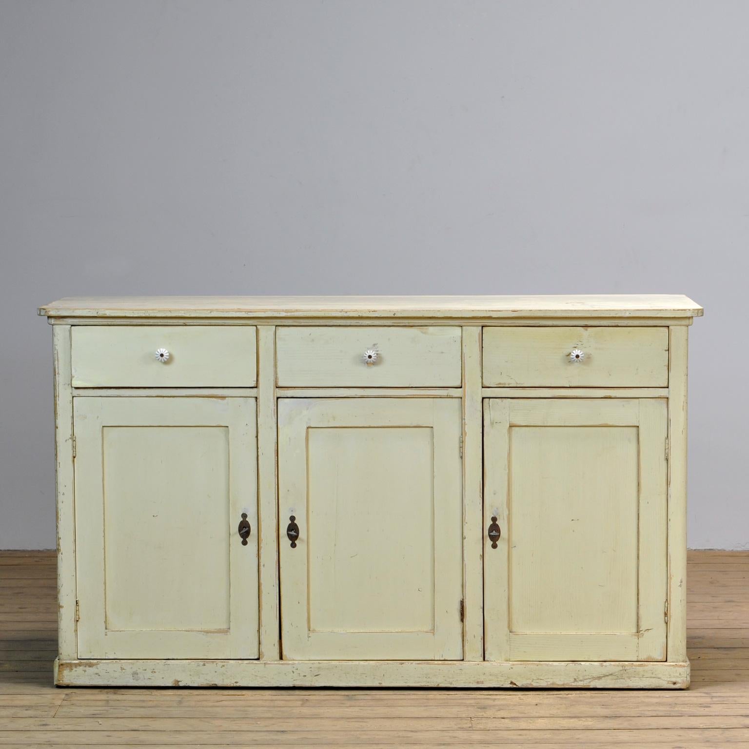 French Pine shopcounter from the 1920's with 3 drawers with porcelain knobs. Behind the 3 doors is another shelf. The paint is original.
  