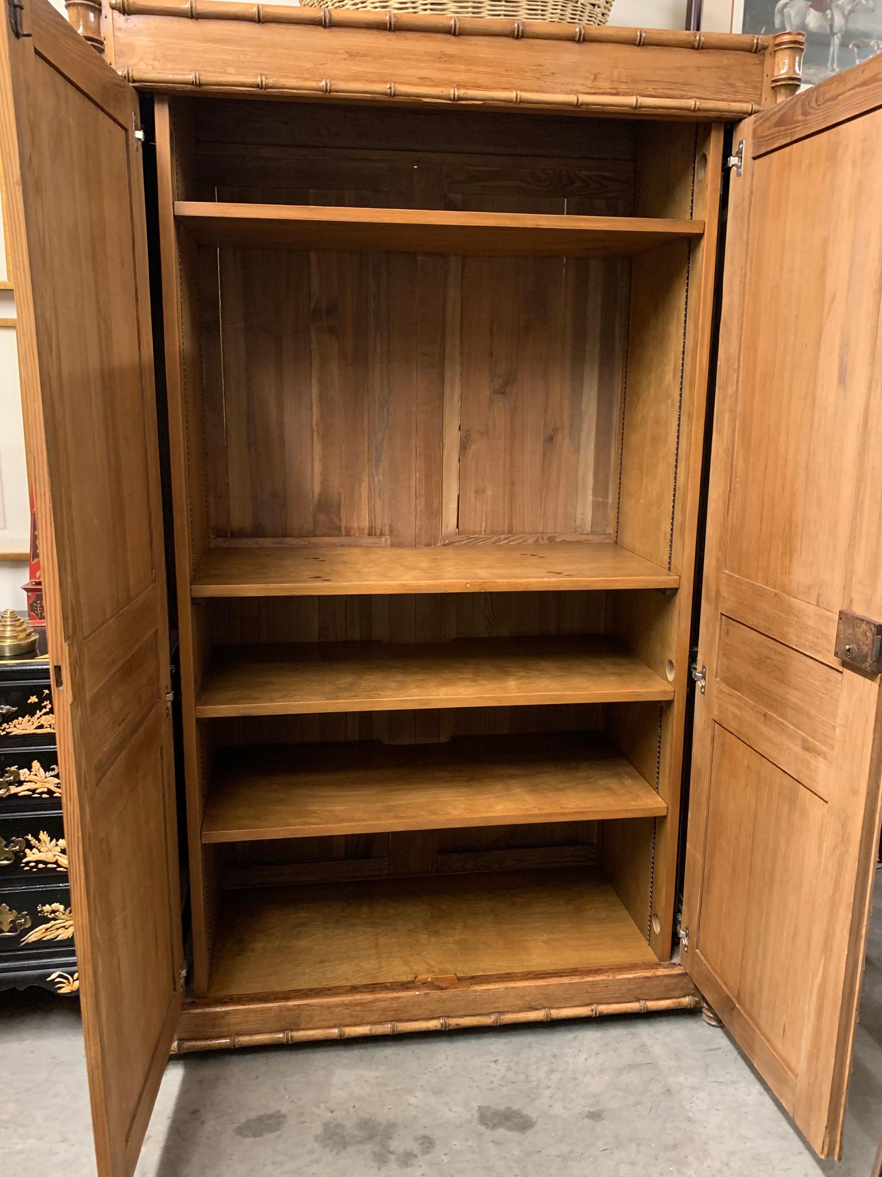 French pine antique two door armoire with faux bamboo turnings. The doors have been altered so that they slide back into the sides of the armoire. The interior has been fitted with strong shelving originally to house a television. The top and bottom