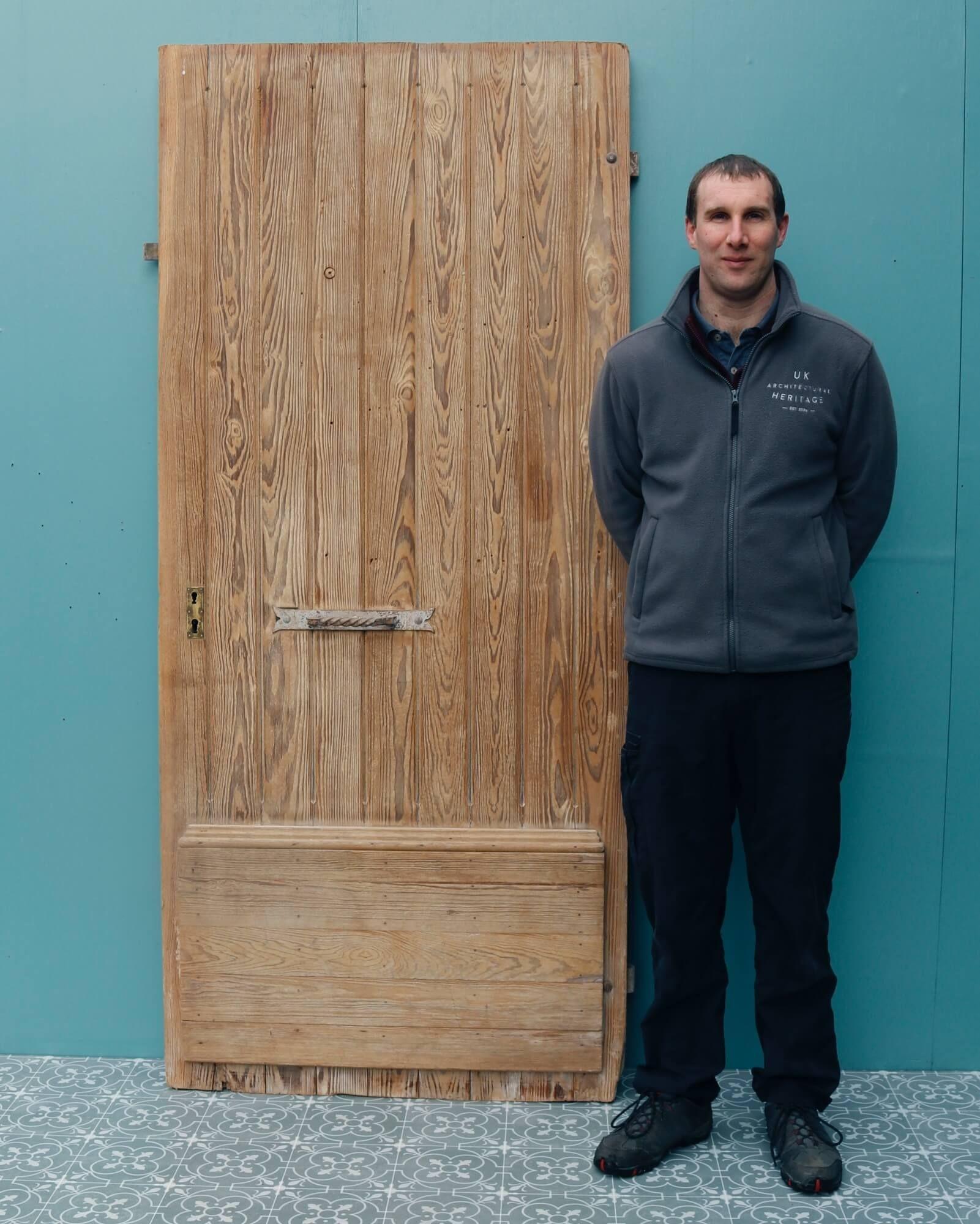 A heavy, strong and substantially constructed pitch pine exterior door originating from mid 19th century France. A character feature for any home, this antique door has a rustic look about it, designed with vertical planks to the front with a
