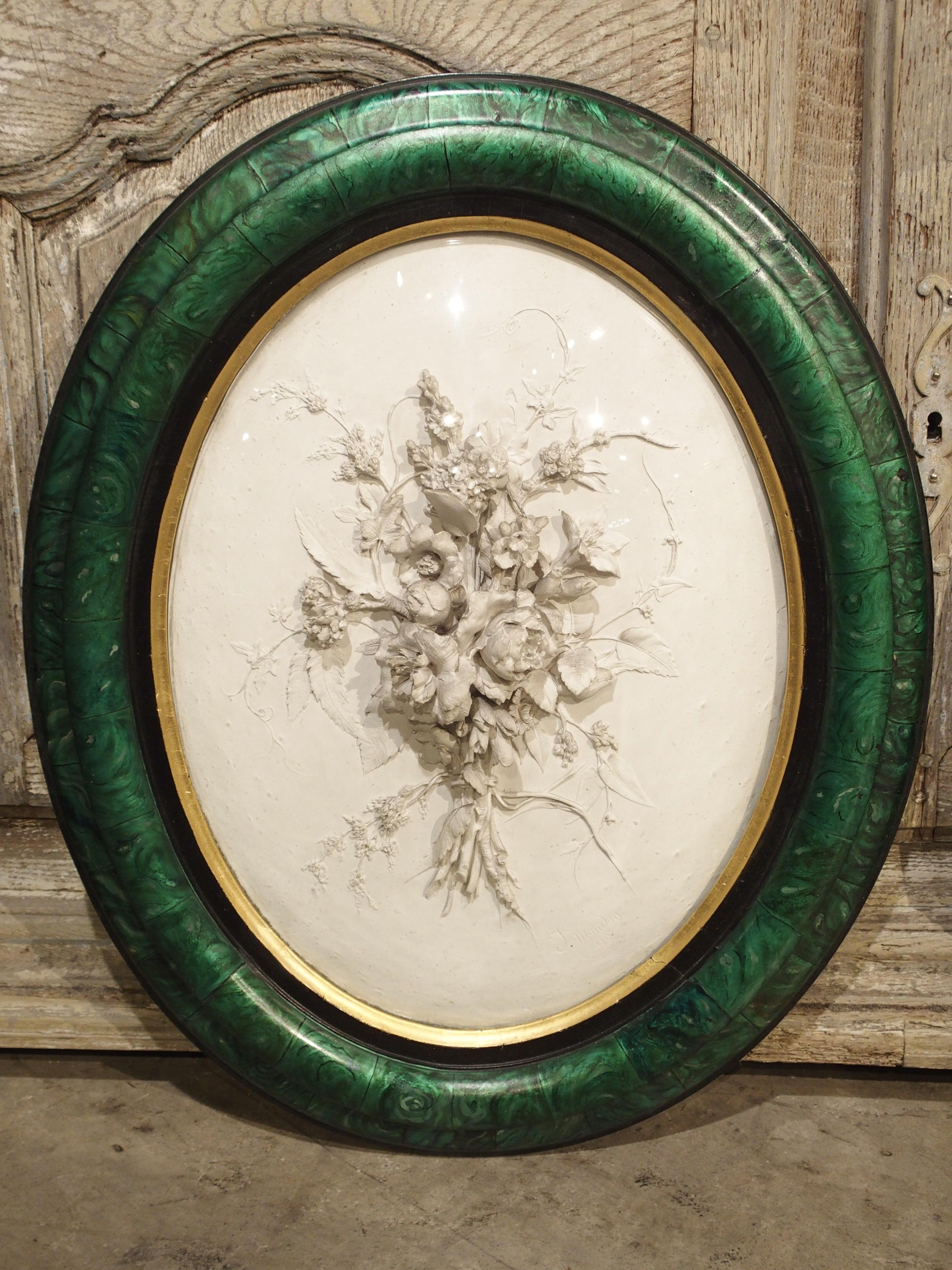 This unique pair of plaster, gros relief floral bouquets represent and spring and fall. They are framed in oval mottled jade colored frames with convex glass. Spring is represented by budding flowers, vines, and roses, while fall is represented by