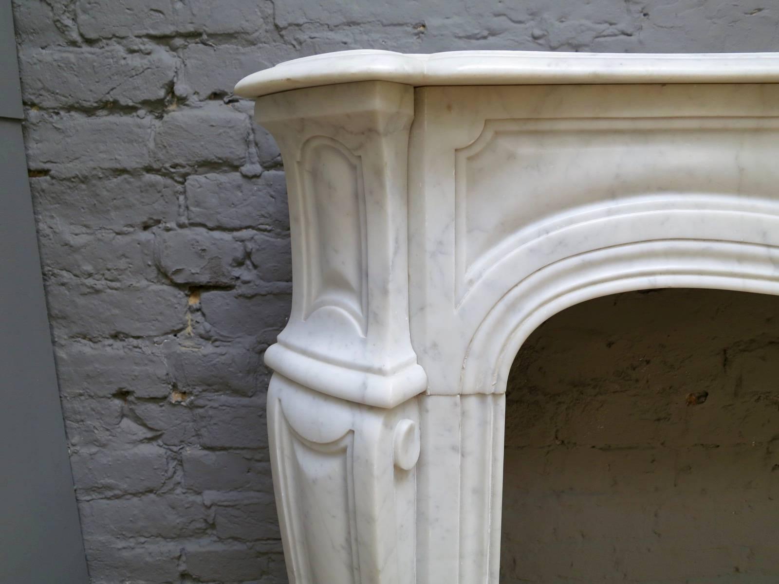 A 19th century French Pompadour fireplace in the Louis XV style, in pale Carrara marble, with canted panelled jambs, conforming panelled frieze and serpentine shelf. The side returns with square brass vents.
Opening size 93 cm W x 85 cm H.